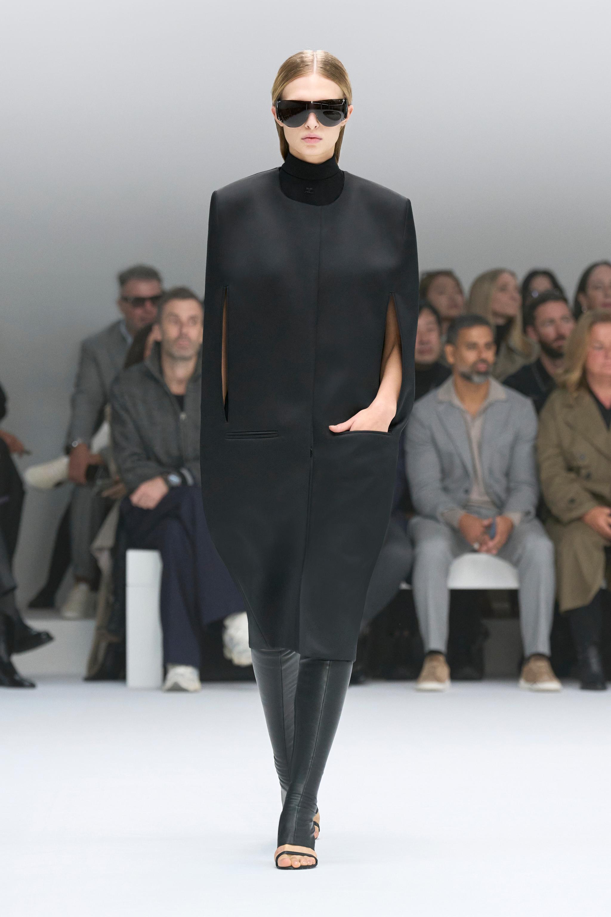 Elegant black dress by Courrèges modeled on runway, perfect for modern fashion statement.