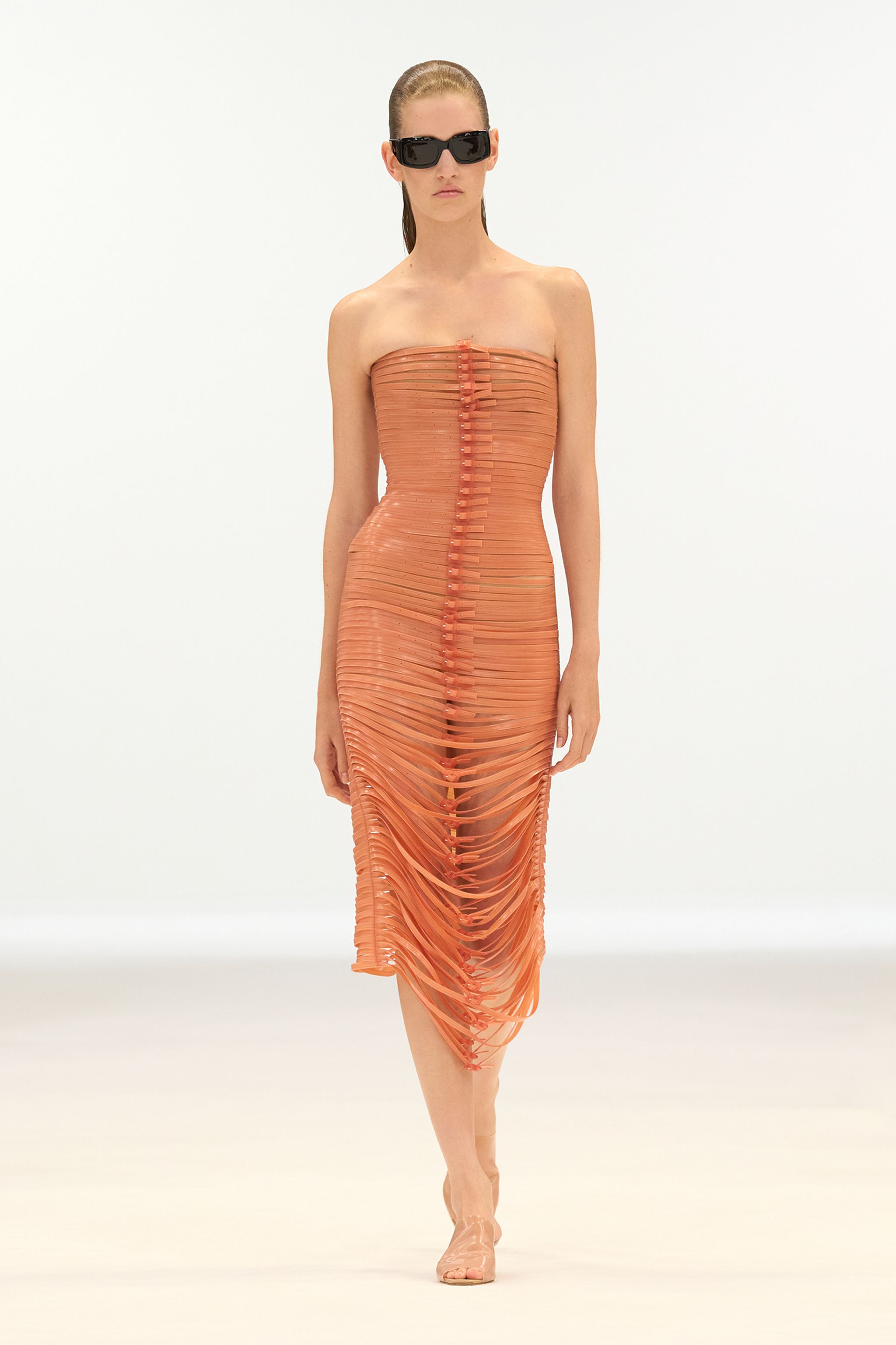Elegant orange slit dress from Courrèges fashion brand, showcased on a runway model.