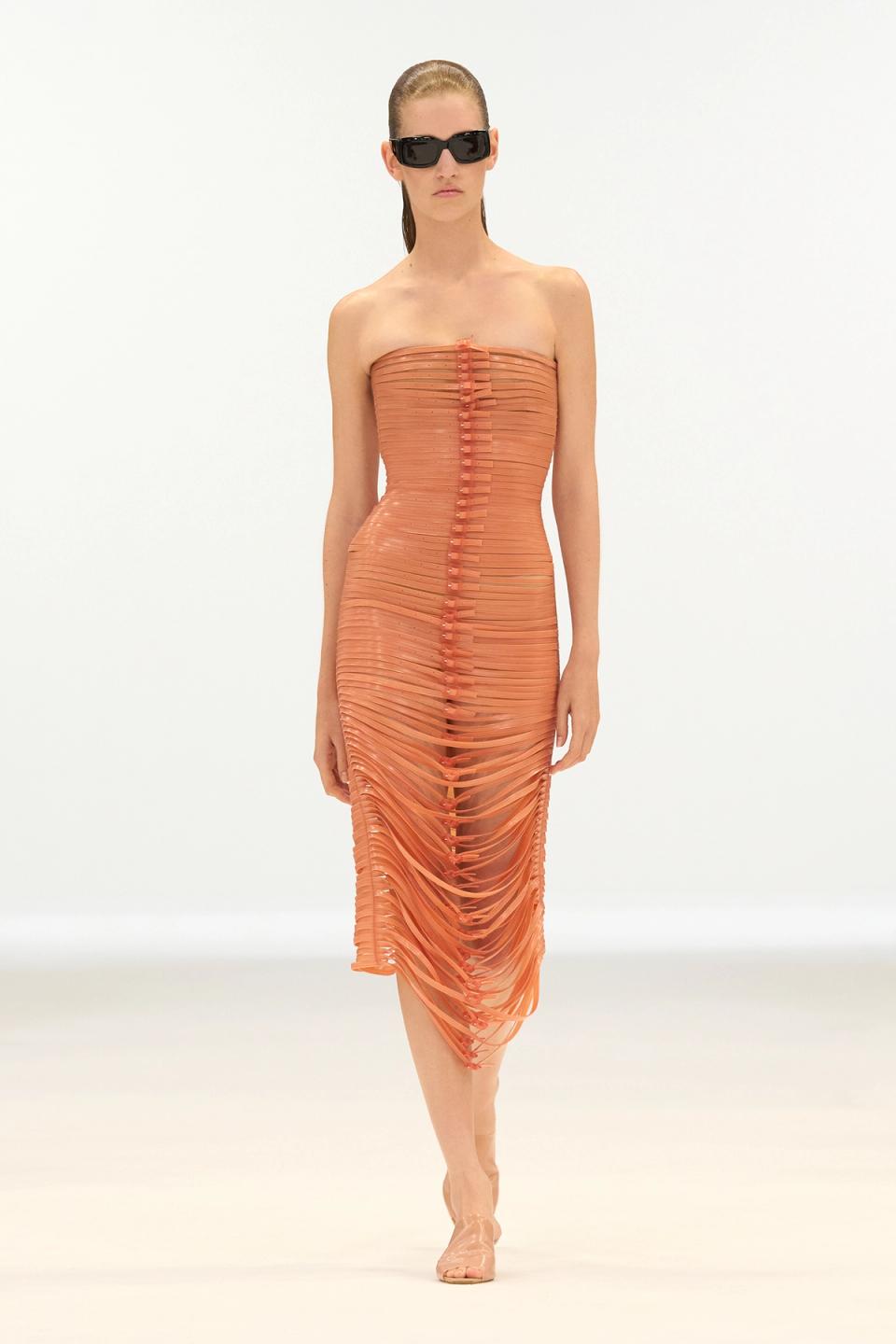 Elegant orange slit dress from Courrèges fashion brand, showcased on a runway model.
