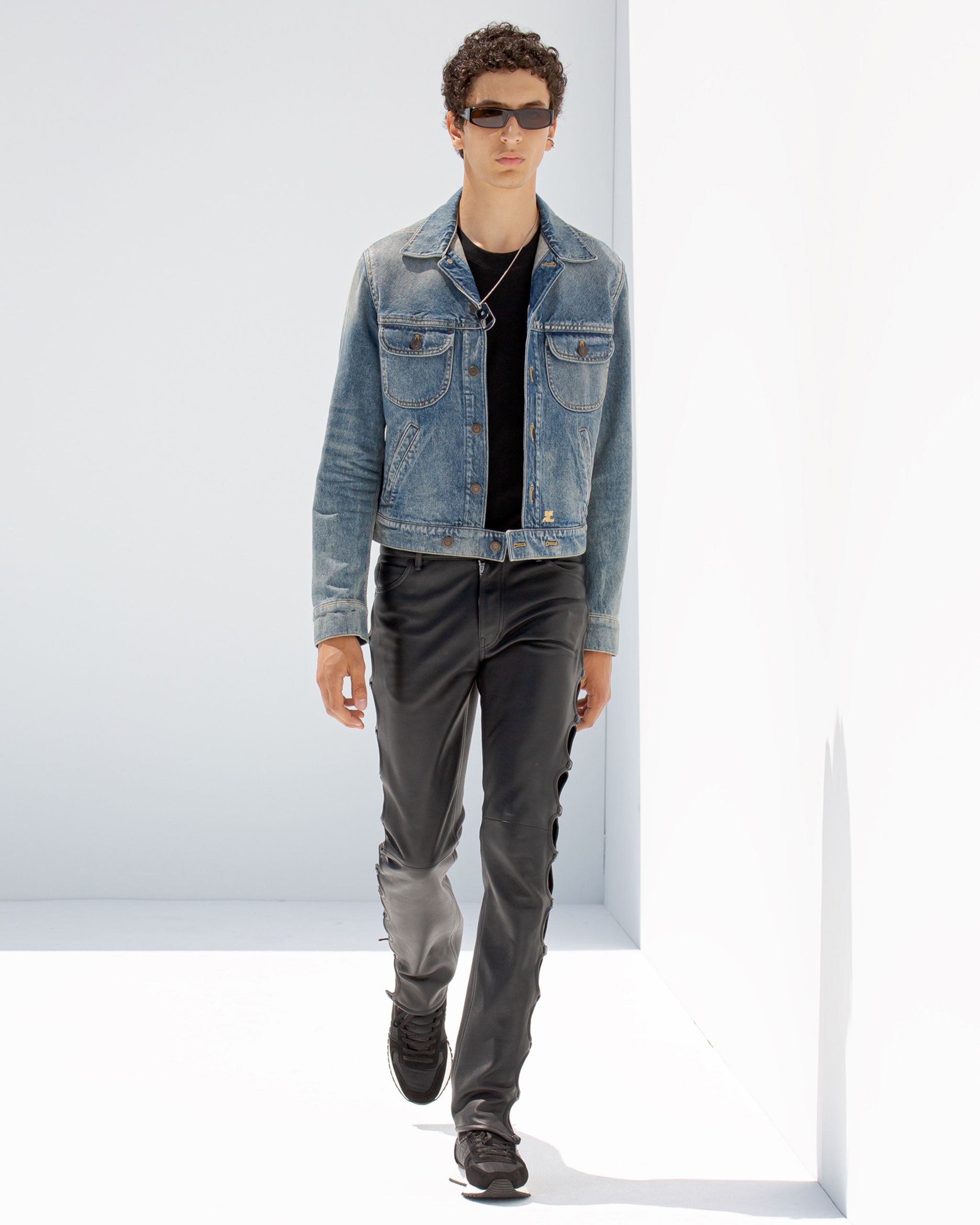 Model wearing denim jacket and black leather pants, showcasing Courrèges fashion style.
