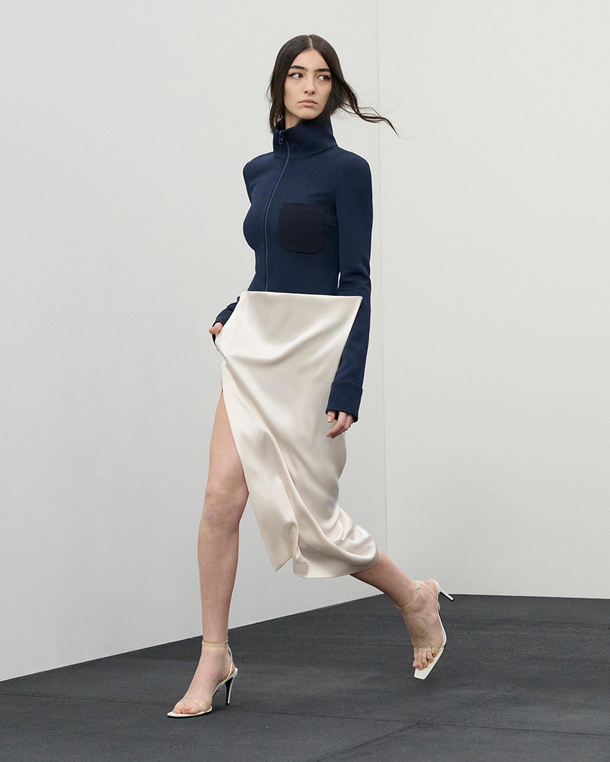 Elegant Courrèges fashion with a navy zip-up top and a draped satin skirt for women.