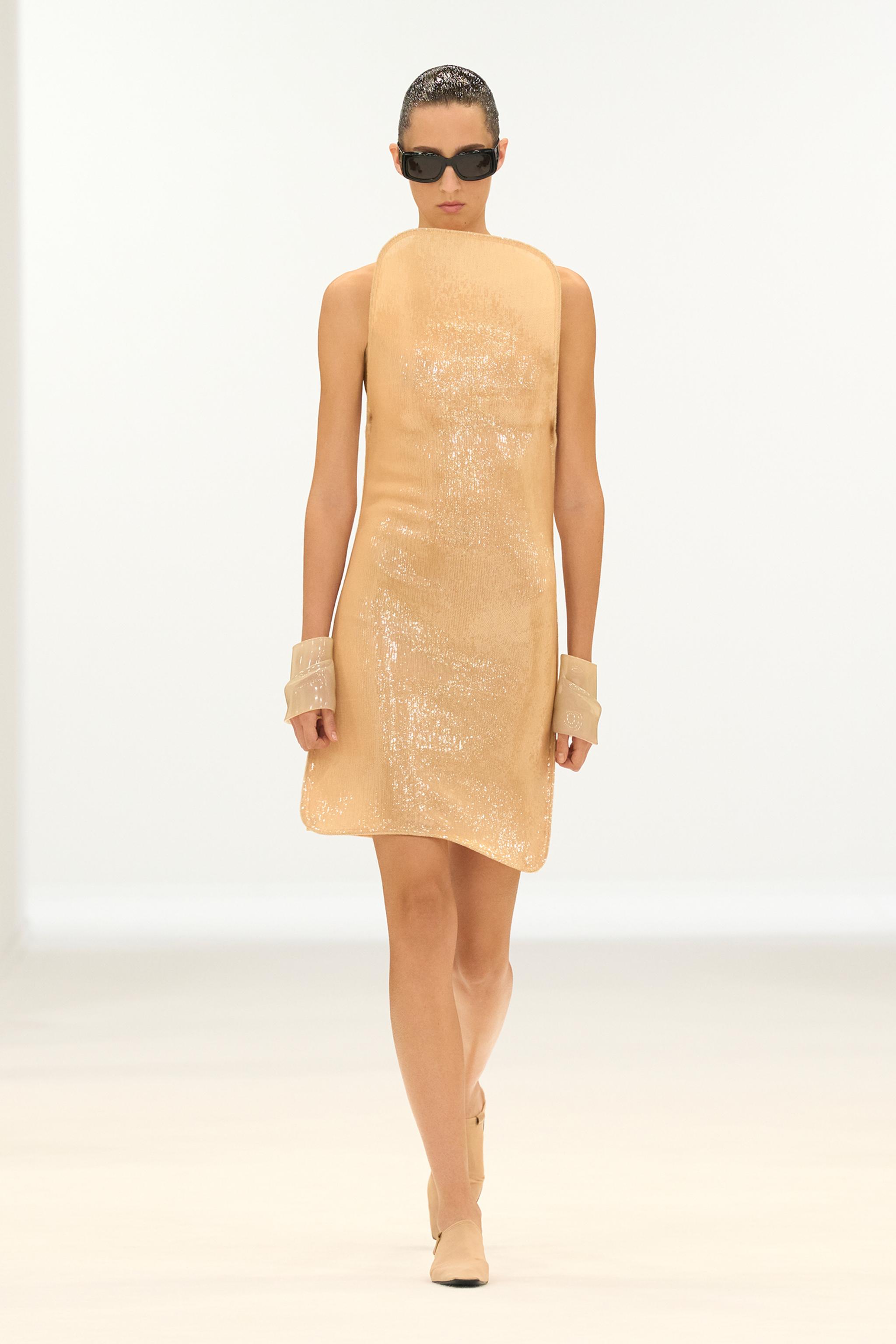Elegant beige sleeveless dress with shiny fabric, styled for Courrèges fashion collection.