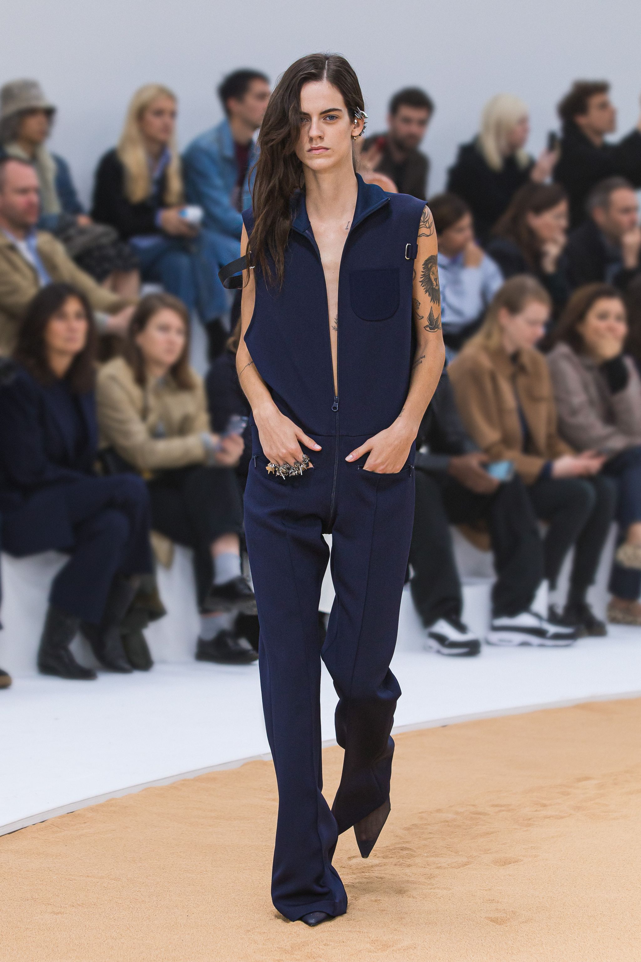 Fashion model wearing a navy jumpsuit with a zipper, on the runway for Courrèges fashion show.