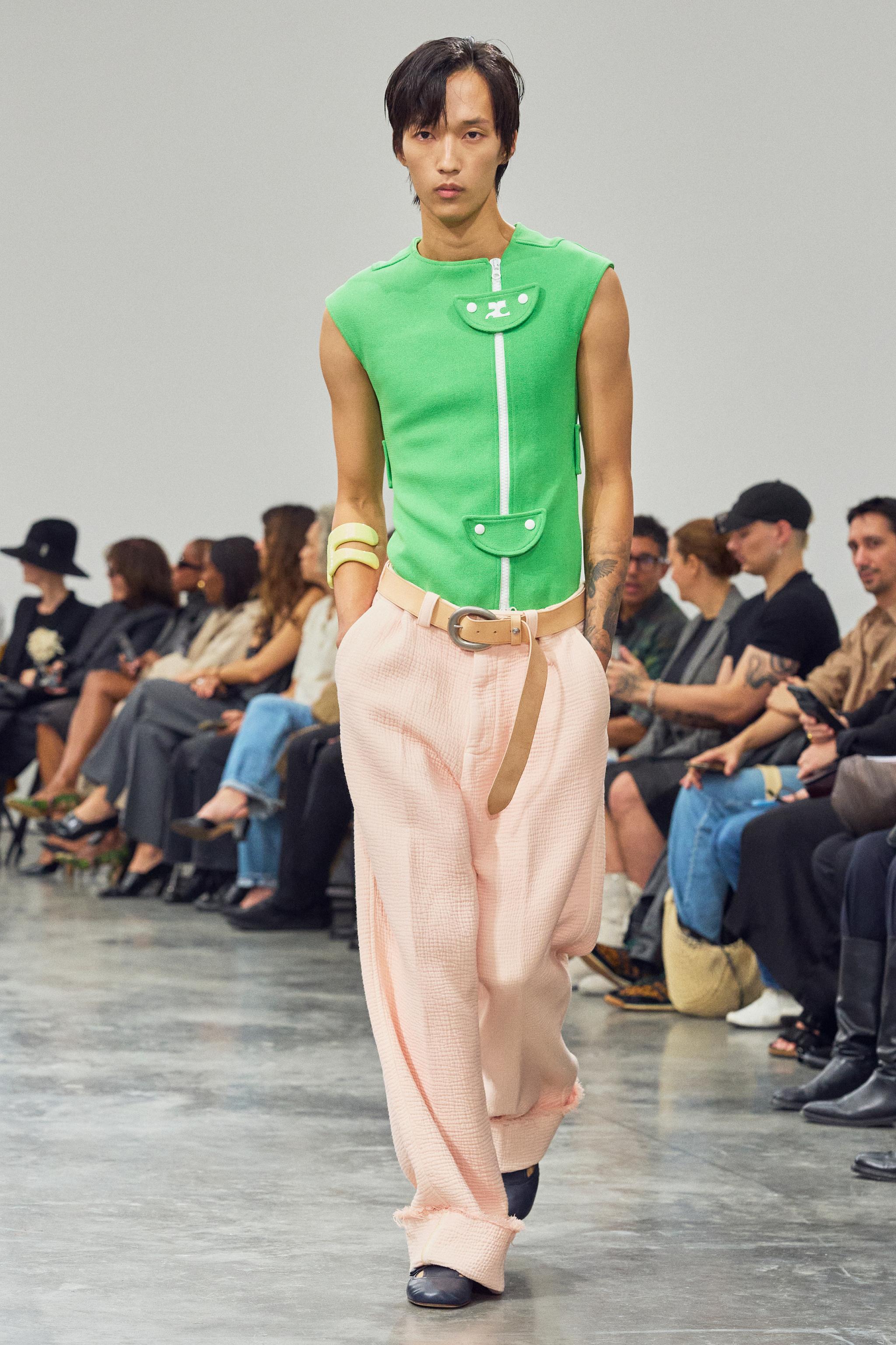 Elegant Courrèges model in vibrant green and pastel pink, showcasing futuristic fashion at a runway show.