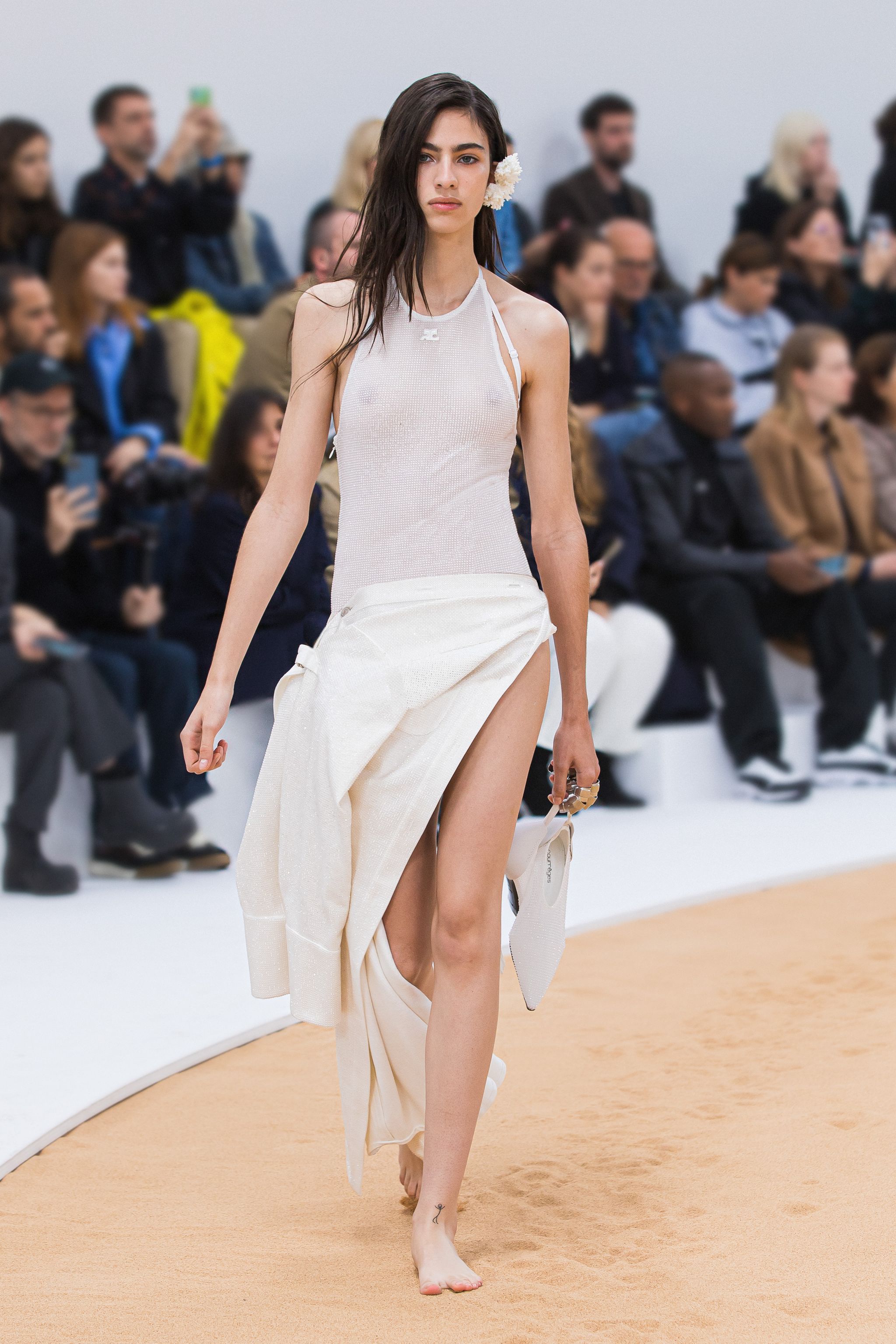 Elegant model walking the runway in a sleek white dress at Courrèges fashion show.