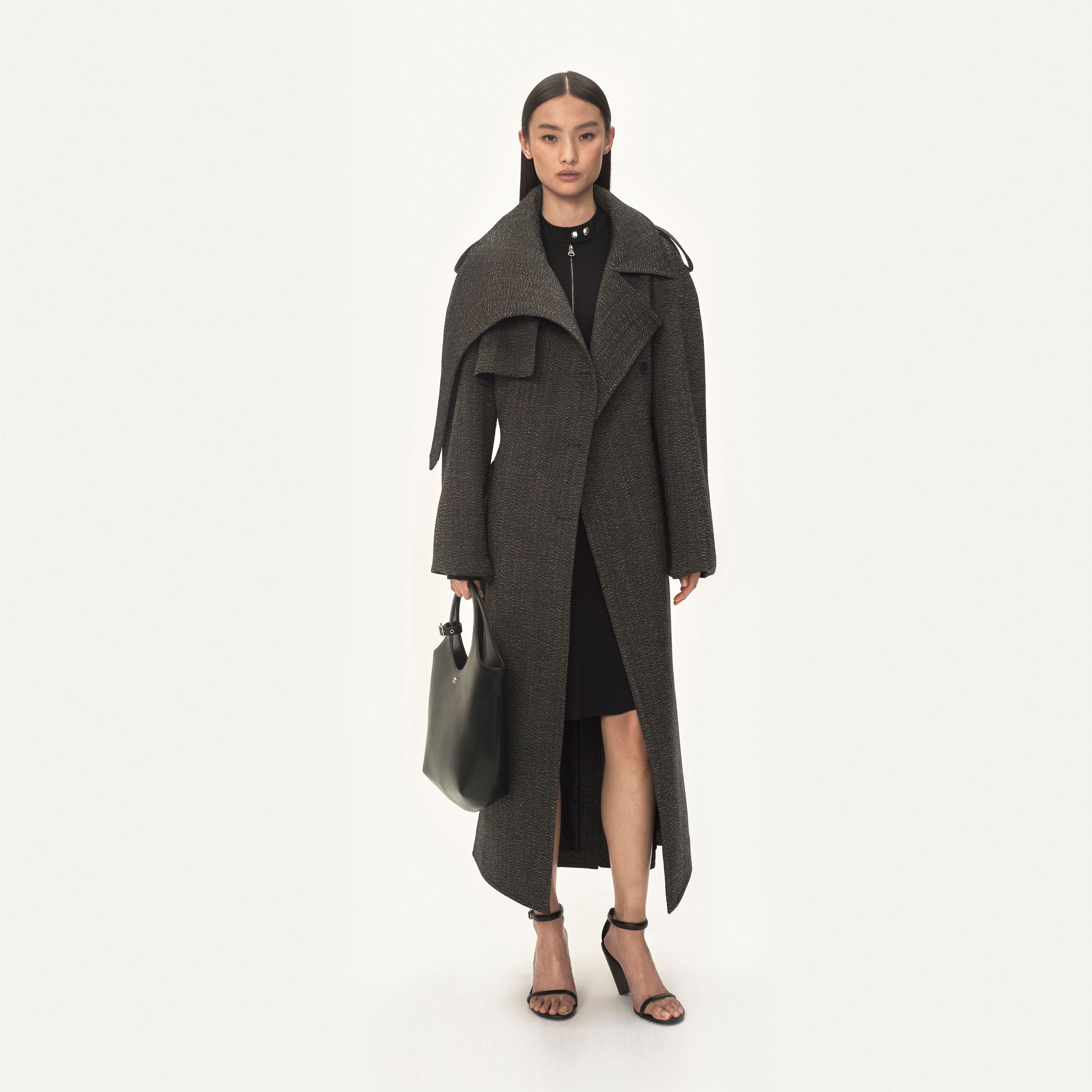 Elegant model wearing a long gray coat by Courrèges, showcasing contemporary fashion.