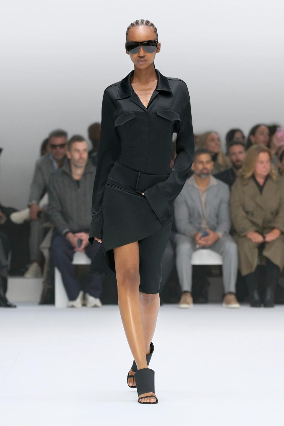 Elegant black Courrèges fashion runway model wearing a stylish sleek outfit and sunglasses.