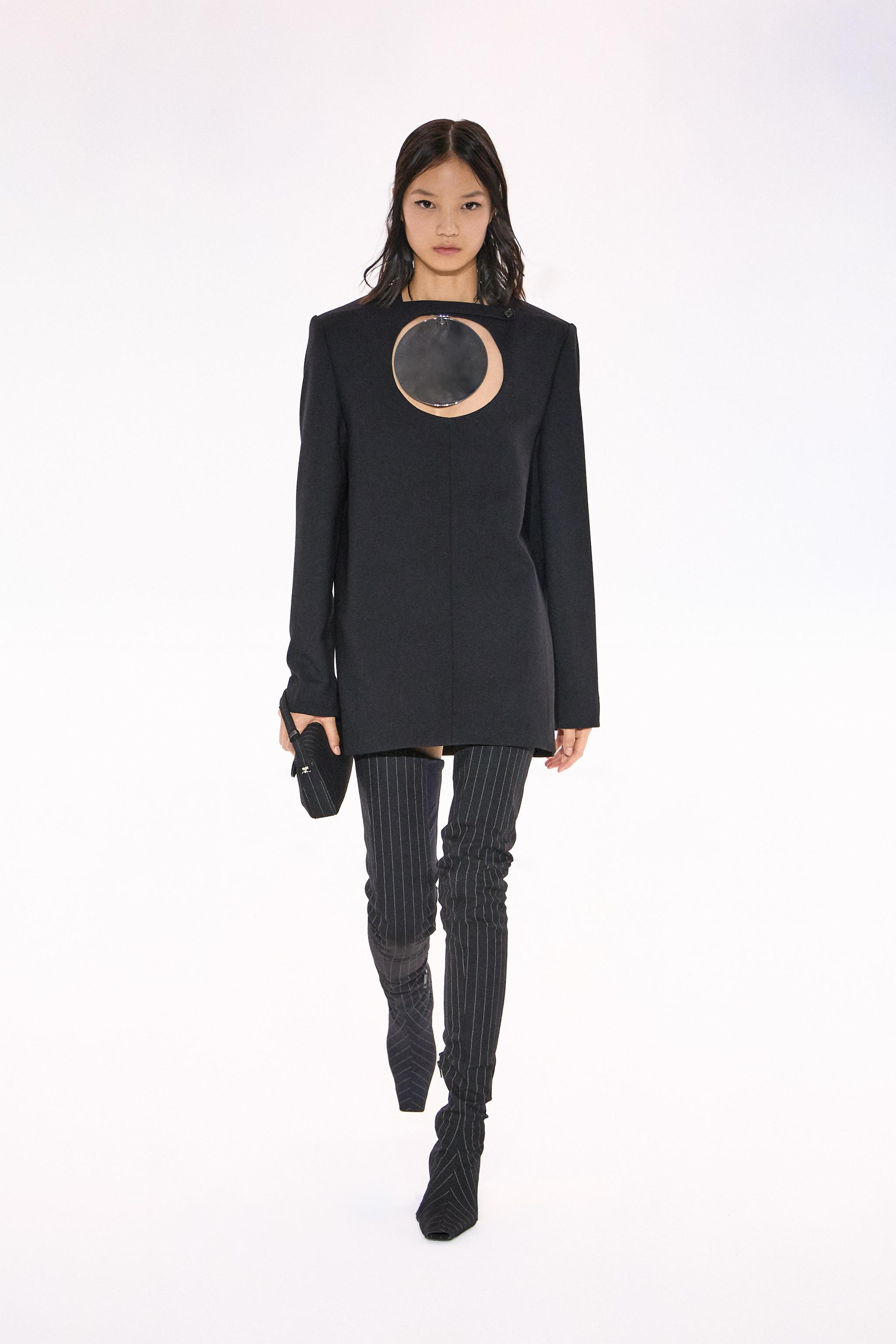Elegant black Courrèges dress with a distinctive circular cutout, on a fashion runway model.
