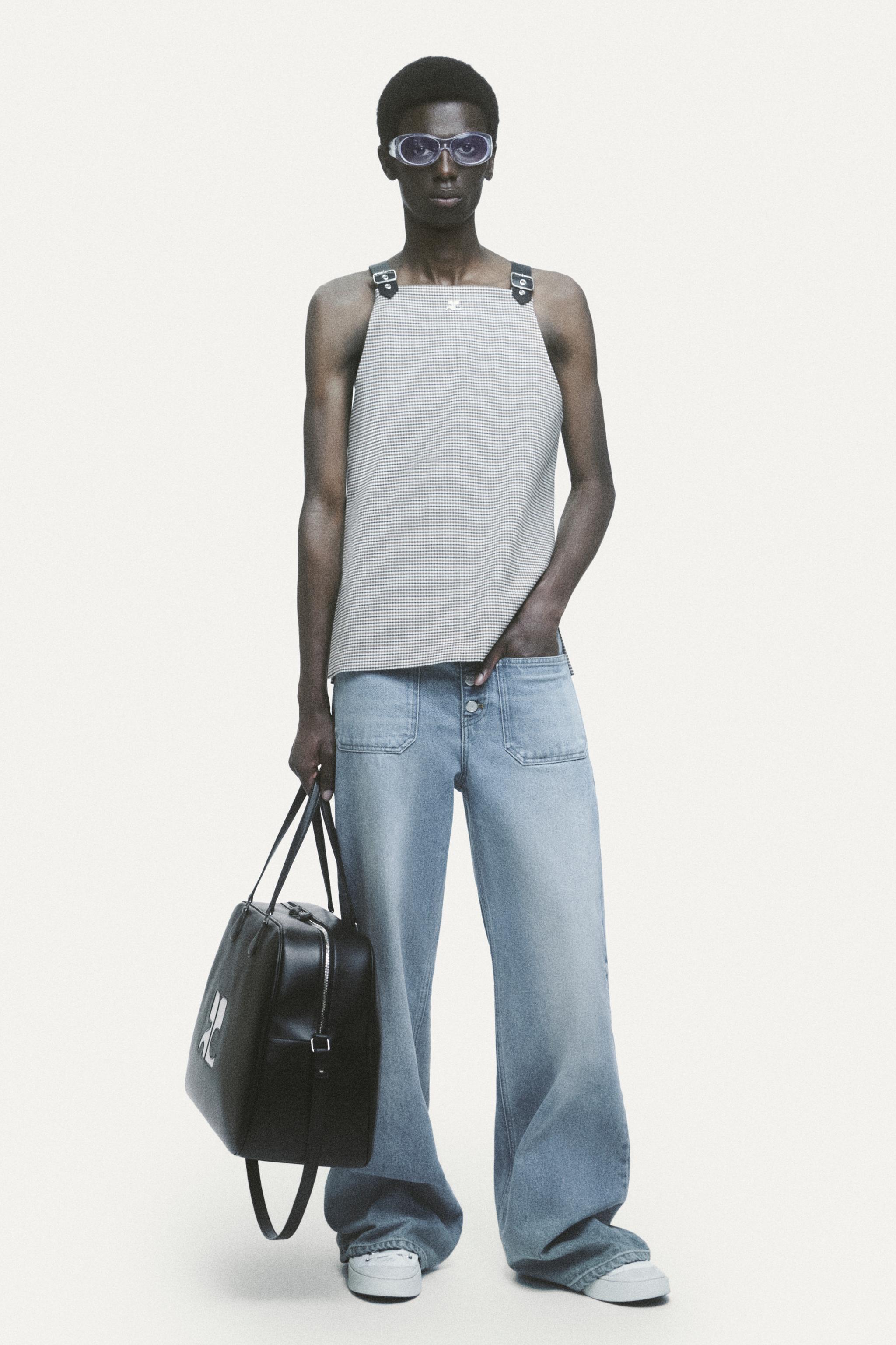 Elegant fashion model wearing Courrèges stylish tank top, wide jeans, and sunglasses for ecommerce.