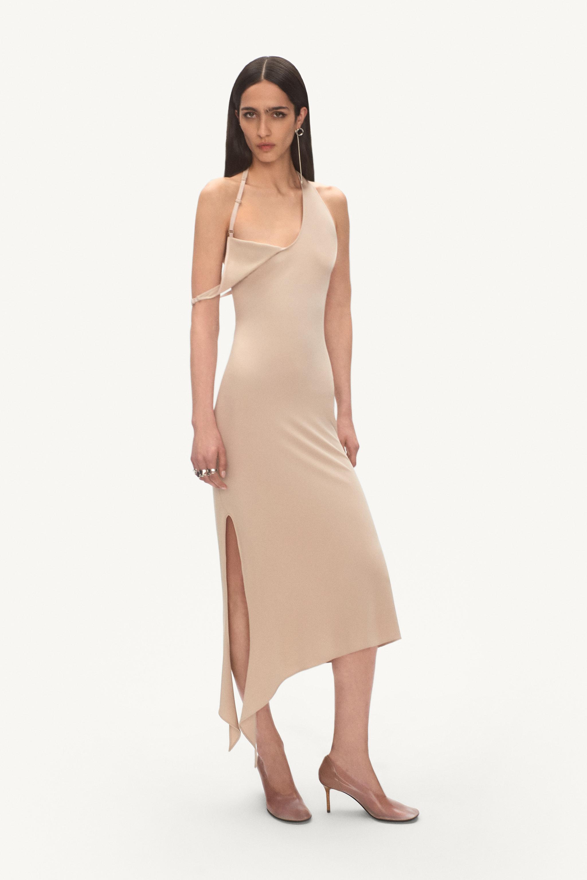 Elegant beige asymmetrical dress by Courrèges, featuring a side slit, on a model for e-commerce.