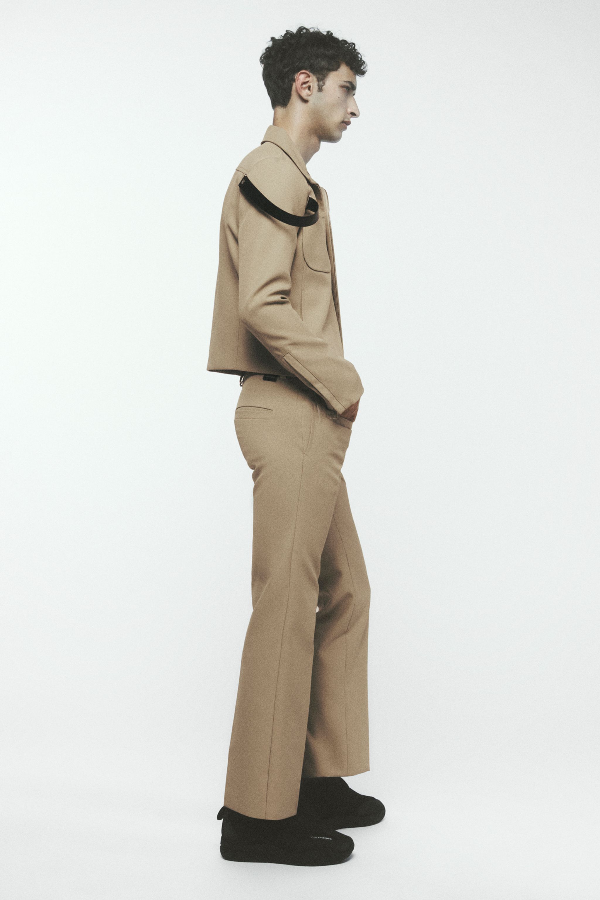 Elegant beige fashion model in cropped jacket and wide-leg pants, Courrèges style.