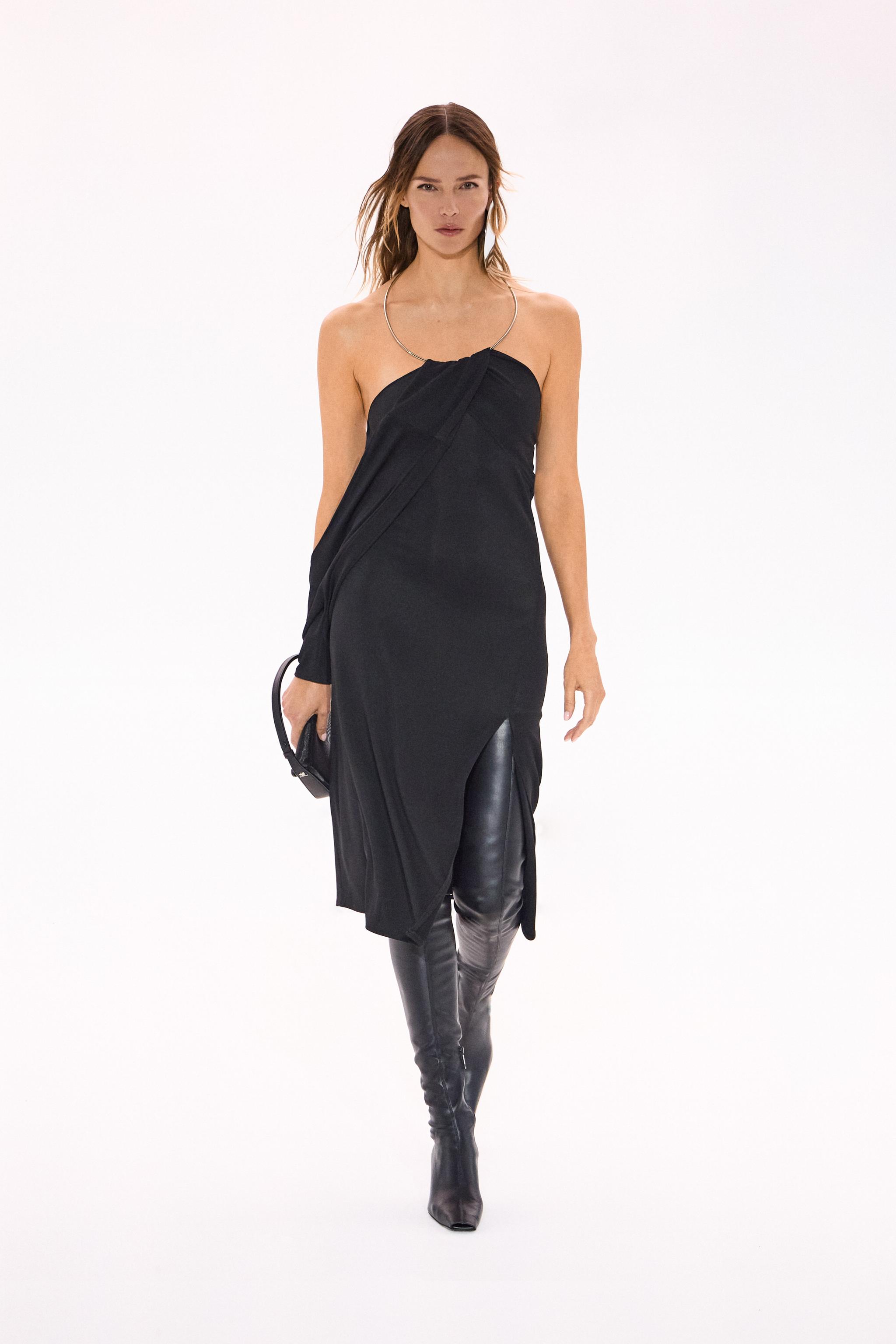 Elegant Courrèges black dress with thigh-high leather boots and stylish silver necklace.