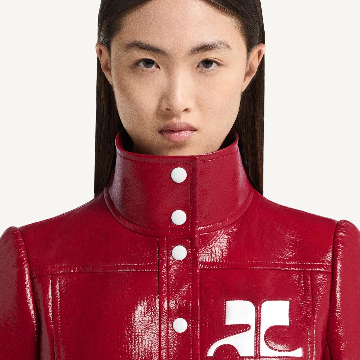 Elegant model wearing a sleek red leather jacket with white branding for Courrèges.