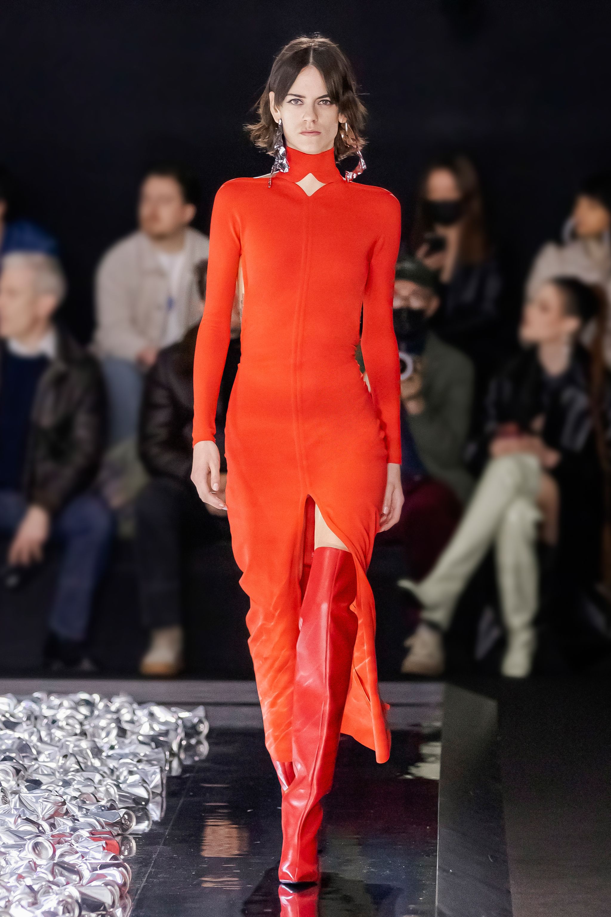 Elegant red dress with thigh-high boots showcased at Courrèges fashion show.