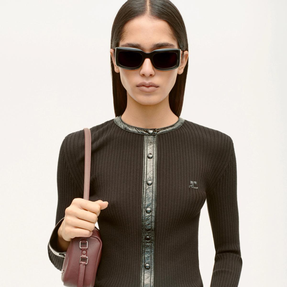 Elegant woman in Courrèges fashion, wearing black sunglasses and a stylish black outfit.