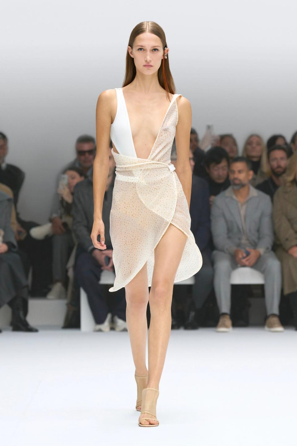 Elegant model wearing Courrèges fashion, white and dotted, walking runway at show.
