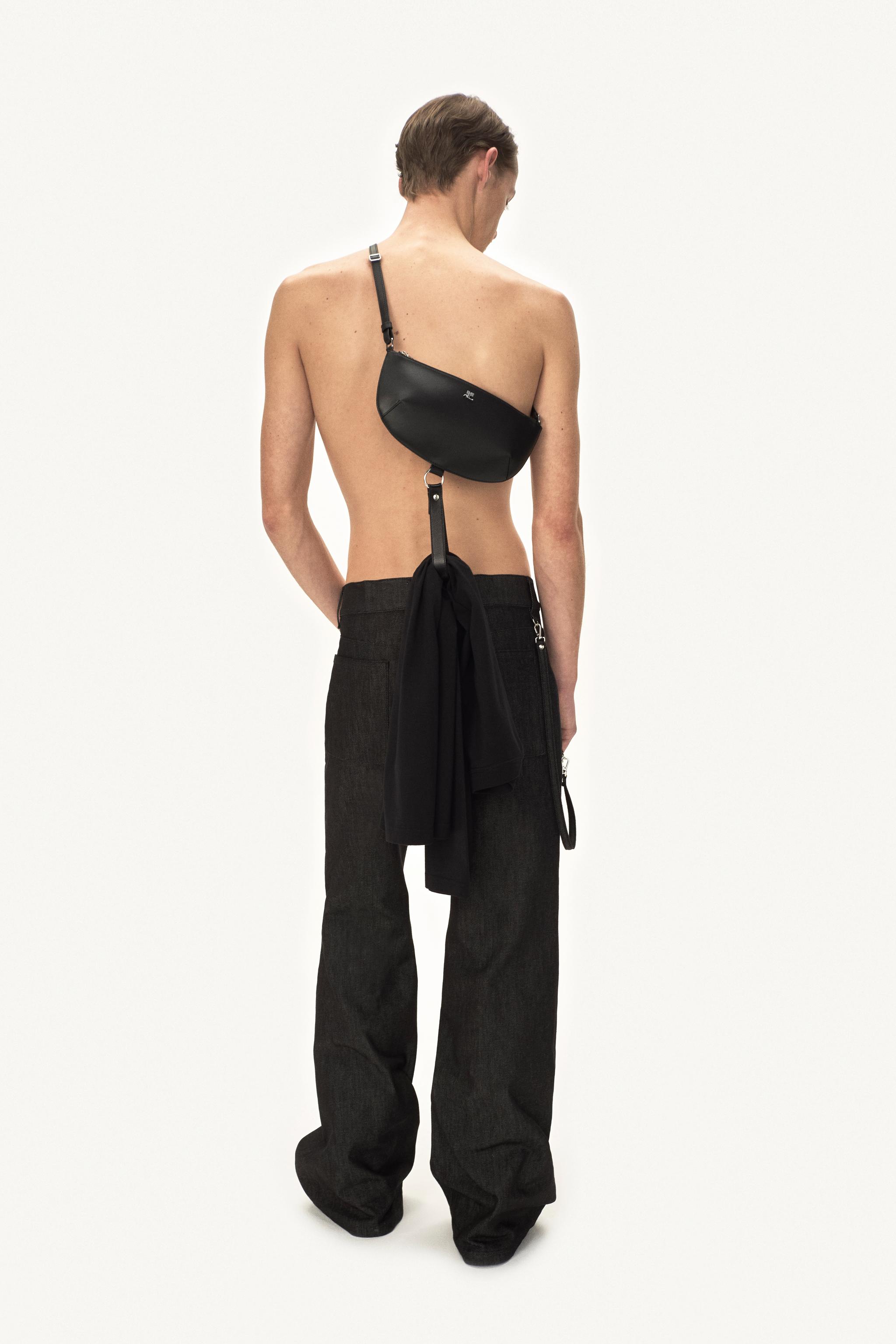Sac bandoulière noir élégant associé à un pantalon ample noir, présenté par un modèle pour Courrèges.
