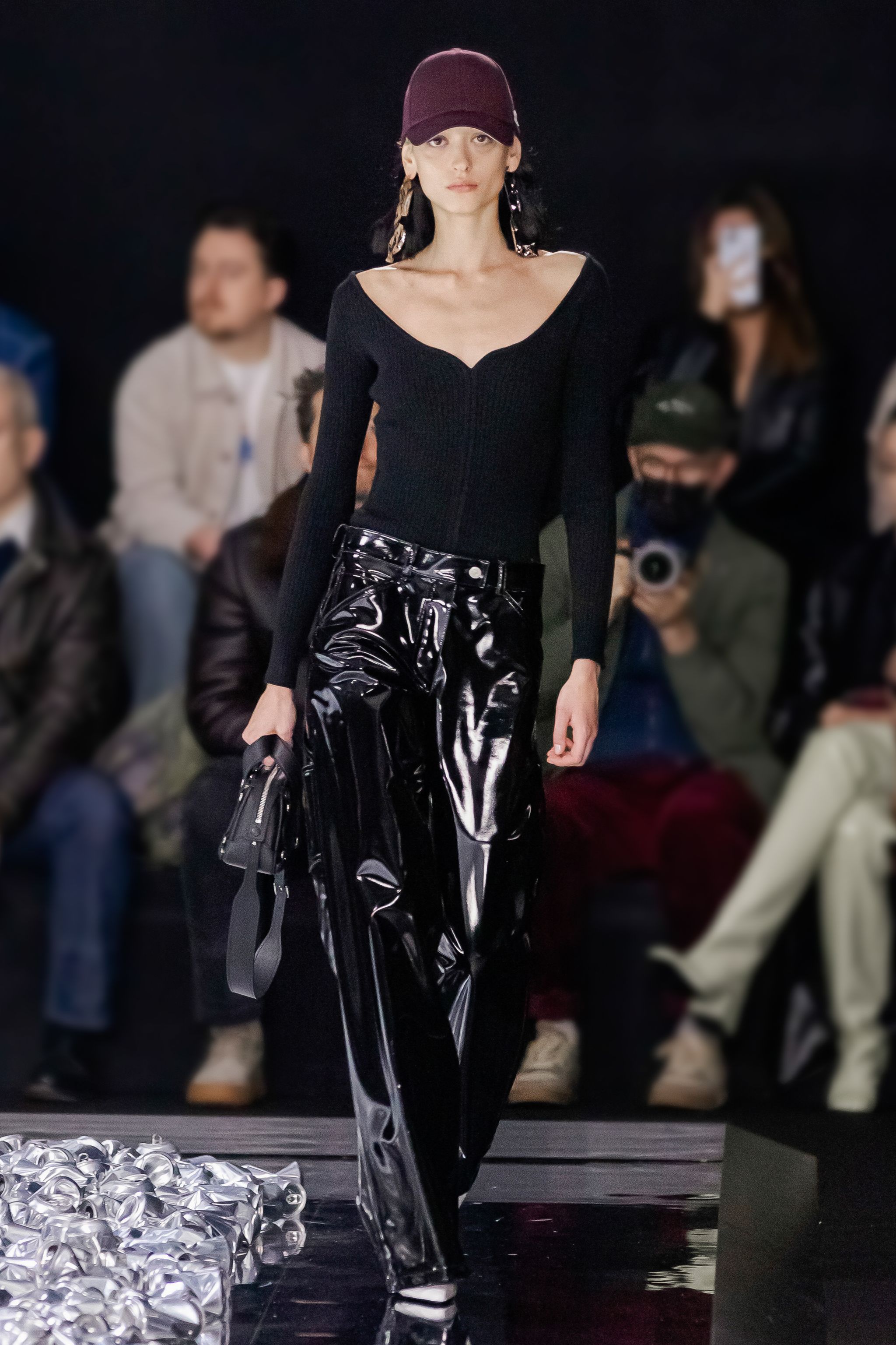 Elegant Courrèges fashion model in black with vinyl pants at a runway show.