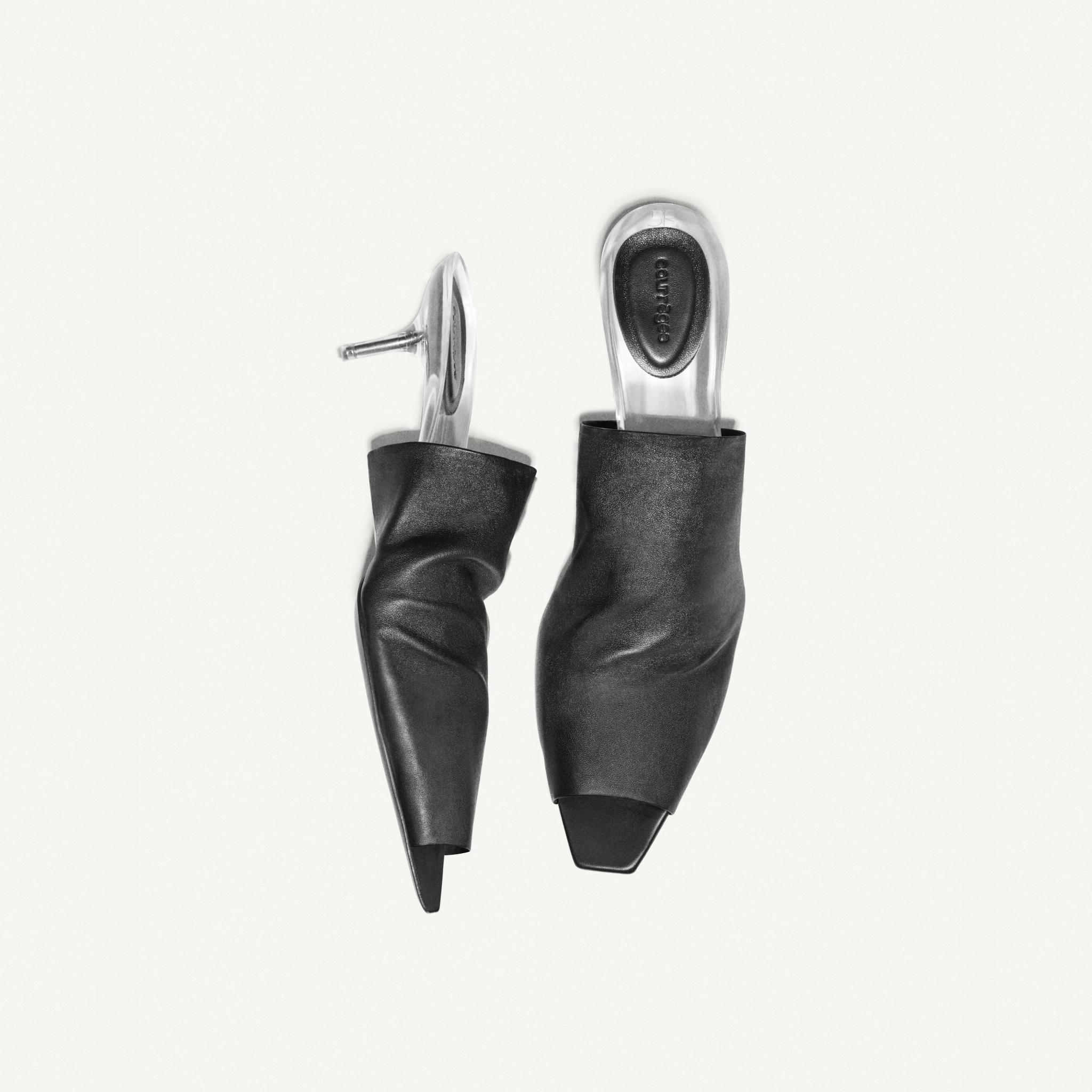 Elegant black leather high heels with transparent heel inserts, part of Courrèges' fashion collection.