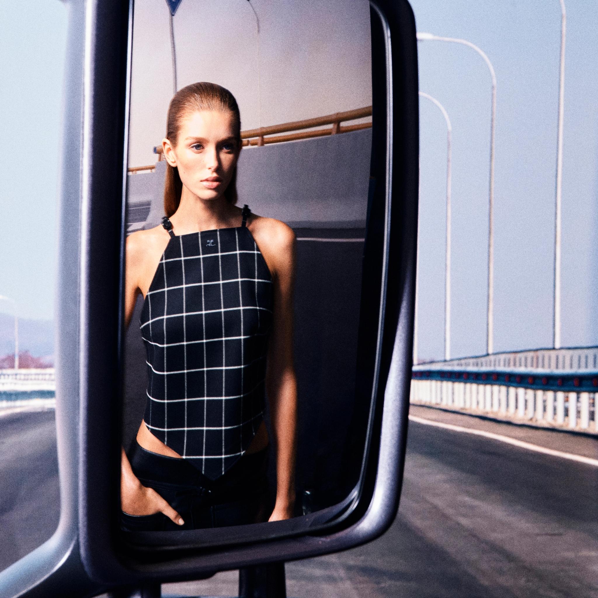 Modèle élégant de la marque Courrèges, portant un haut à carreaux noir et blanc chic.