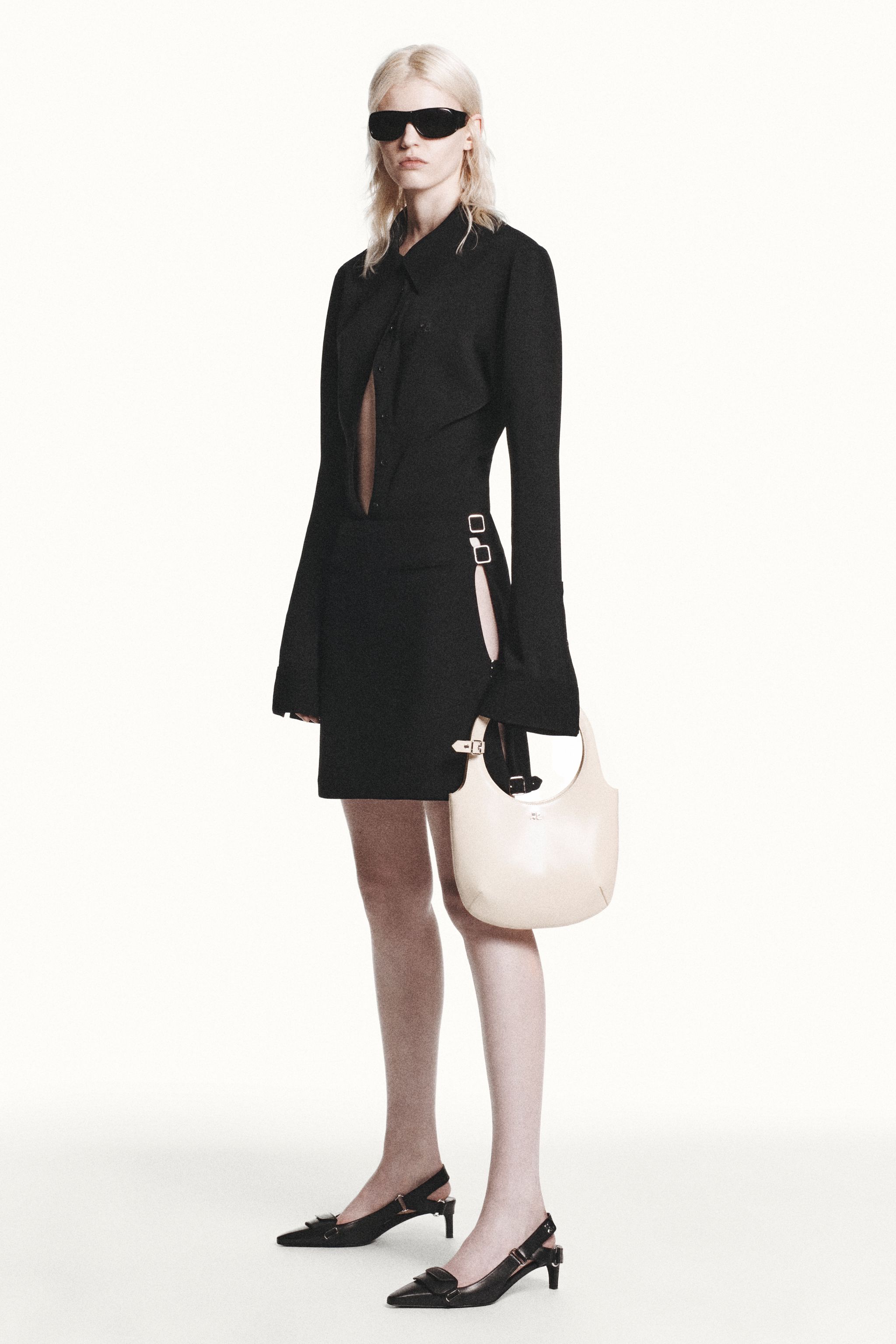 Elegant black Courrèges dress with cut-outs, paired with stylish accessories on a fashion model.