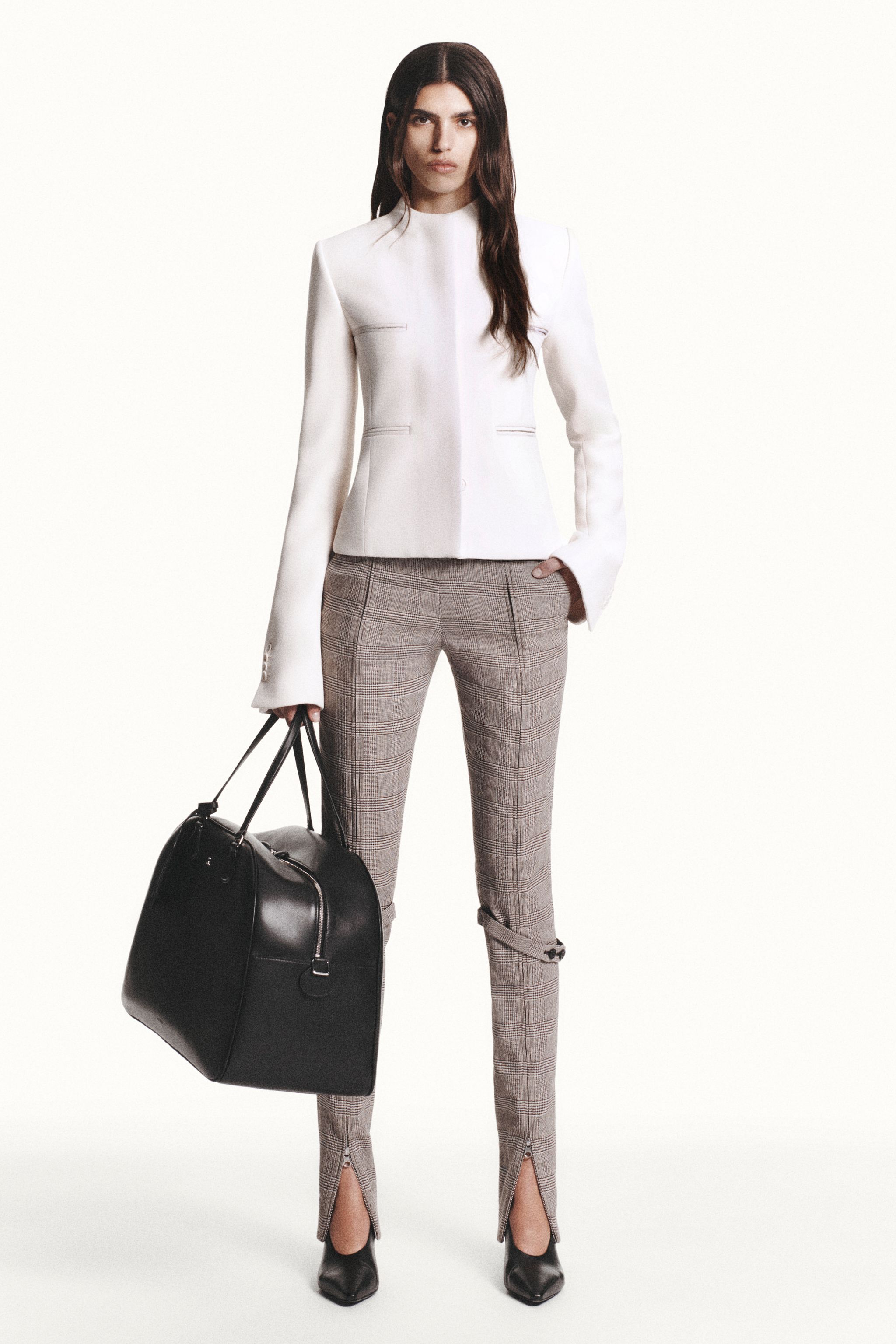 Elegant woman in tailored white blazer, plaid pants, and black heels for Courrèges fashion.