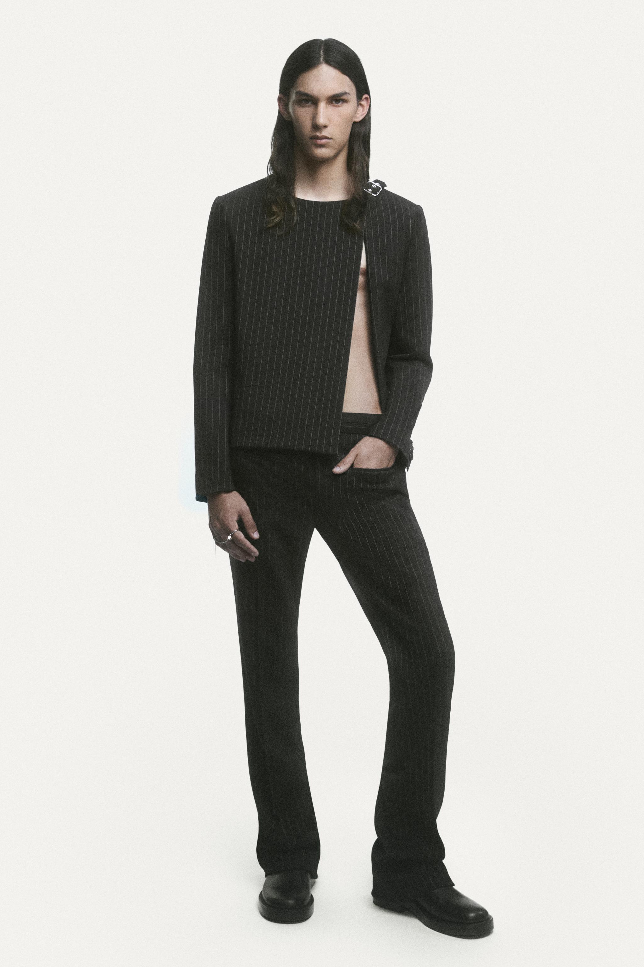 Elegant male model in a black pinstripe suit showcased on Courrèges e-commerce website.