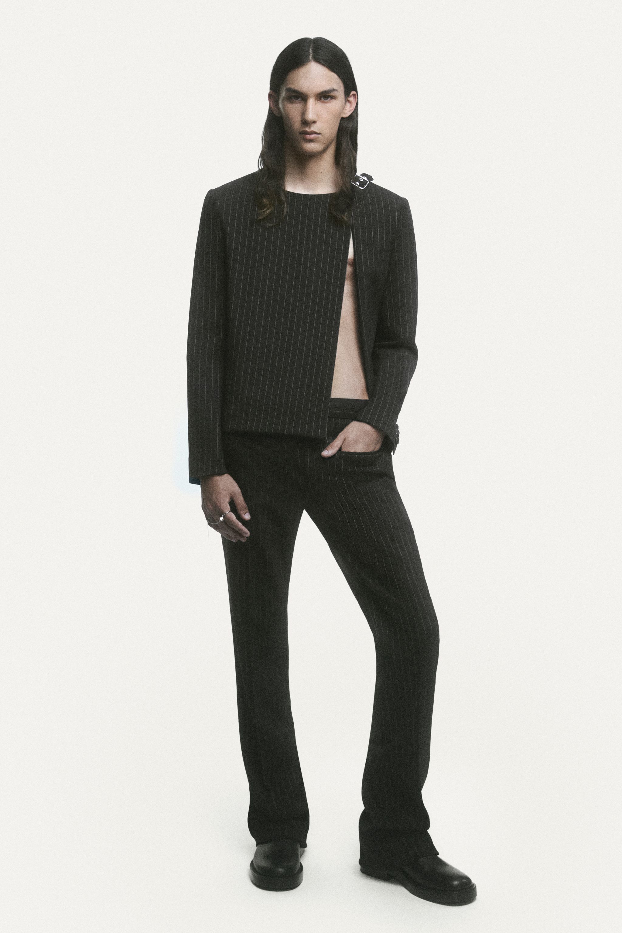 Elegant black pinstripe suit from Courrèges, worn by a model on a minimalist fashion shoot.