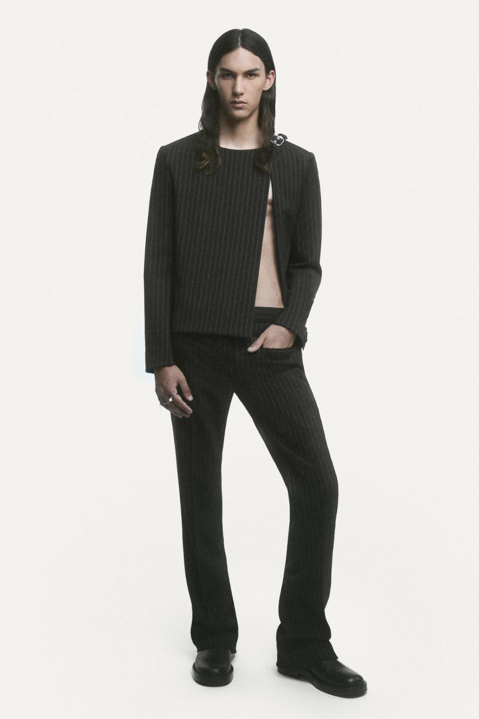 Elegant black pinstripe suit from Courrèges, worn by a model on a minimalist fashion shoot.
