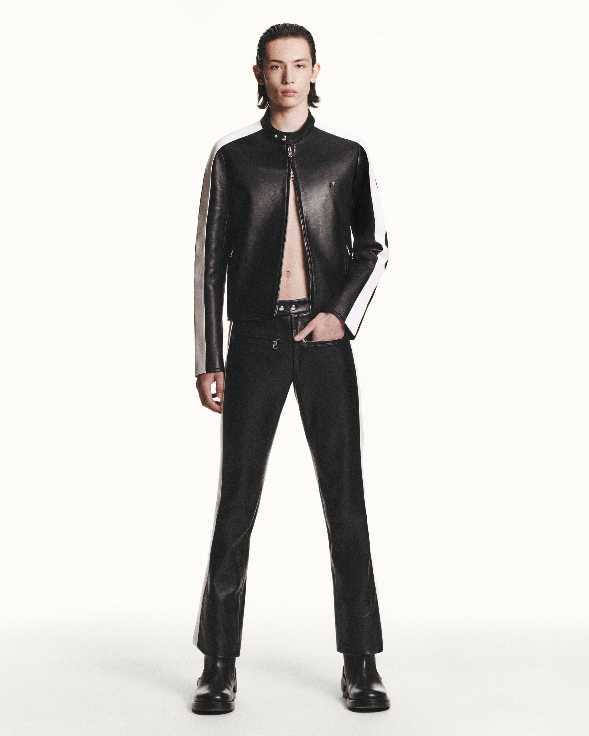 Elegant model in black leather Courrèges jacket and pants, showcasing modern fashion style.