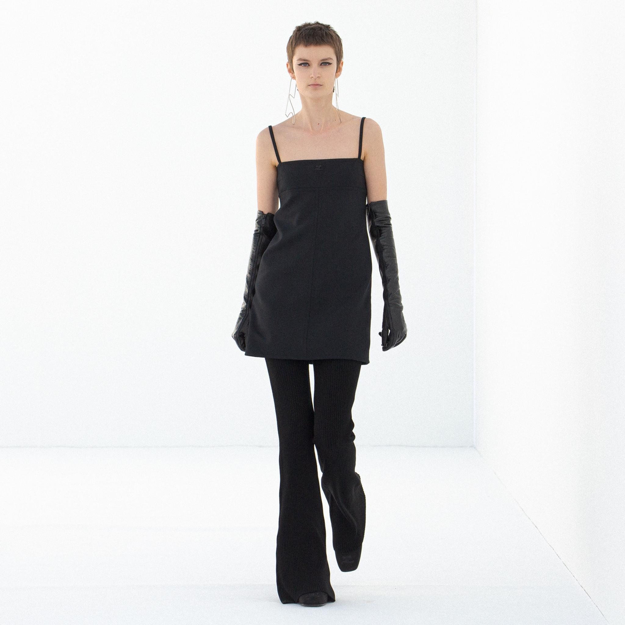 Robe noire élégante à bretelles spaghetti et gants longs, présentée sur un mannequin pour Courrèges.