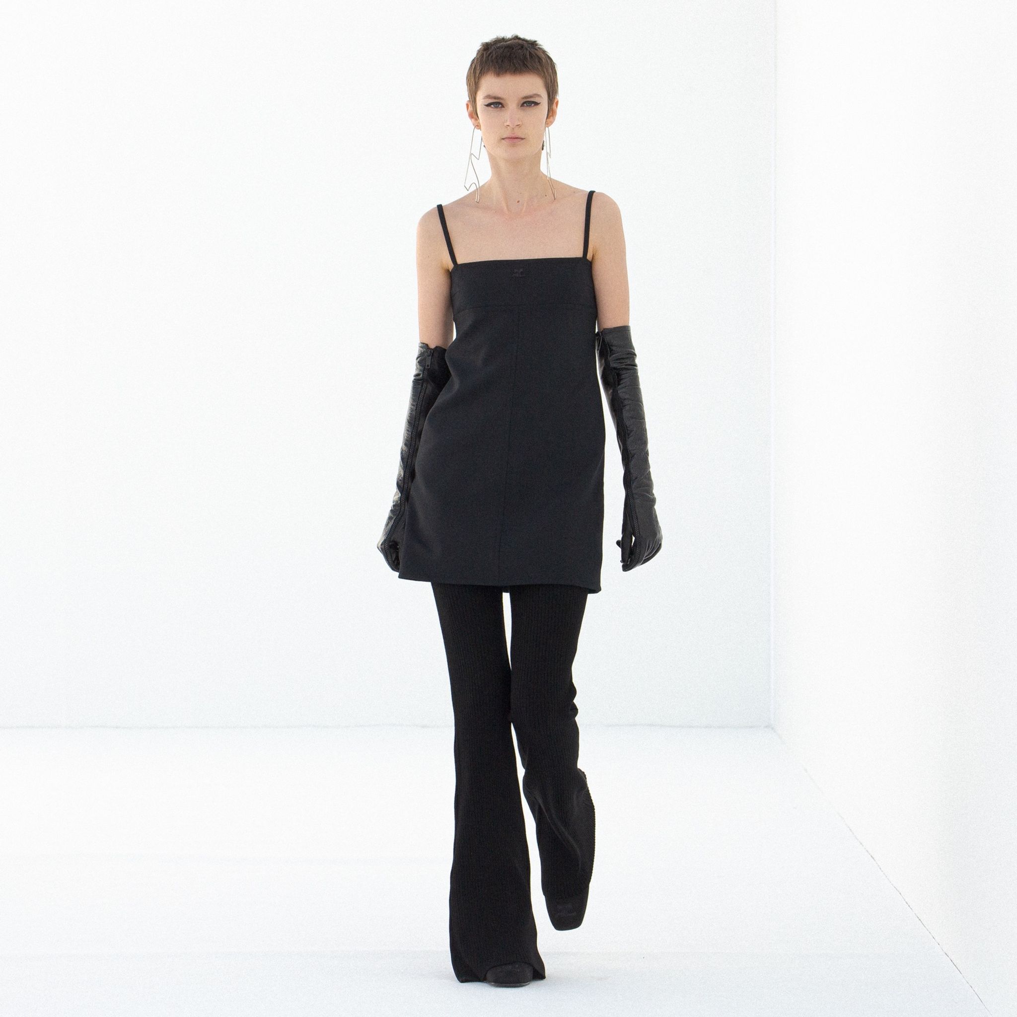 Elegant black dress with spaghetti straps and long gloves, showcased on a model for Courrèges.