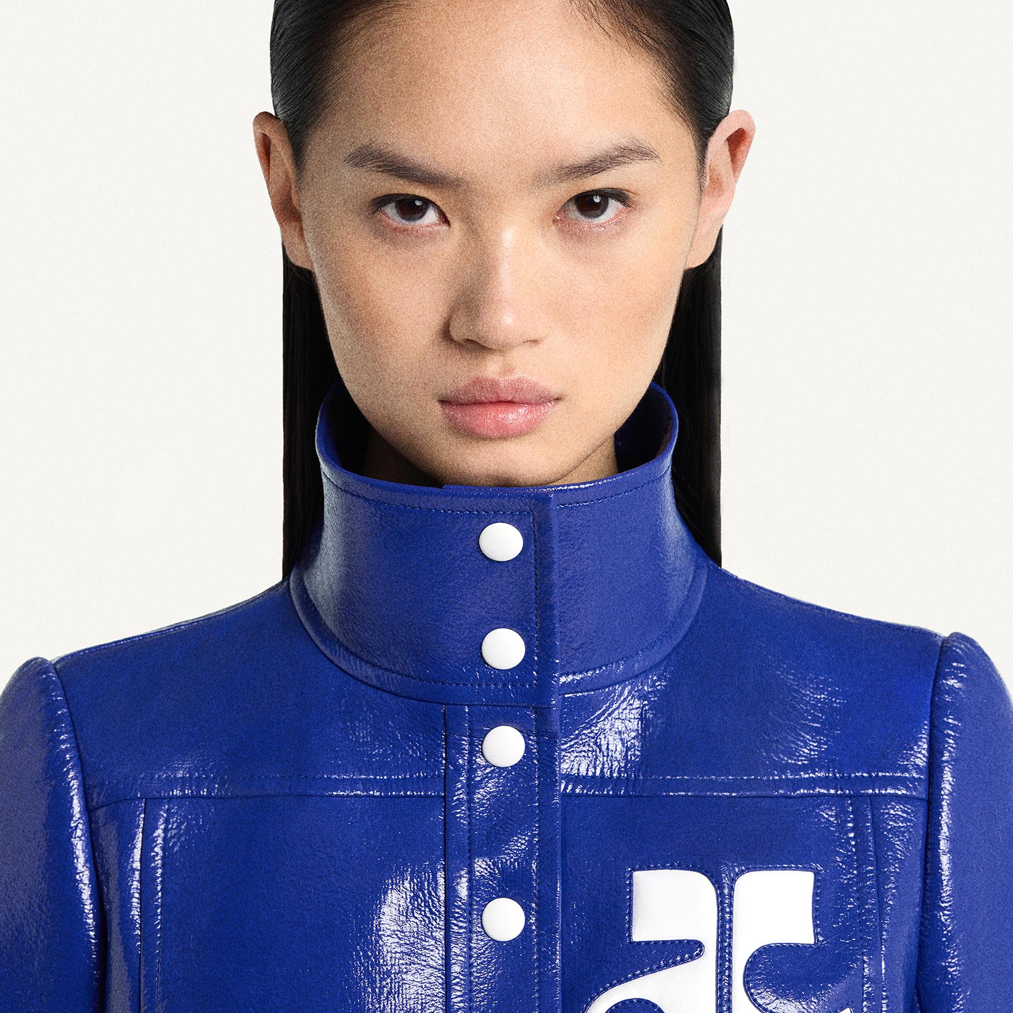 Elegant model wearing a blue leather high-neck jacket, featured on Courrèges e-commerce site.