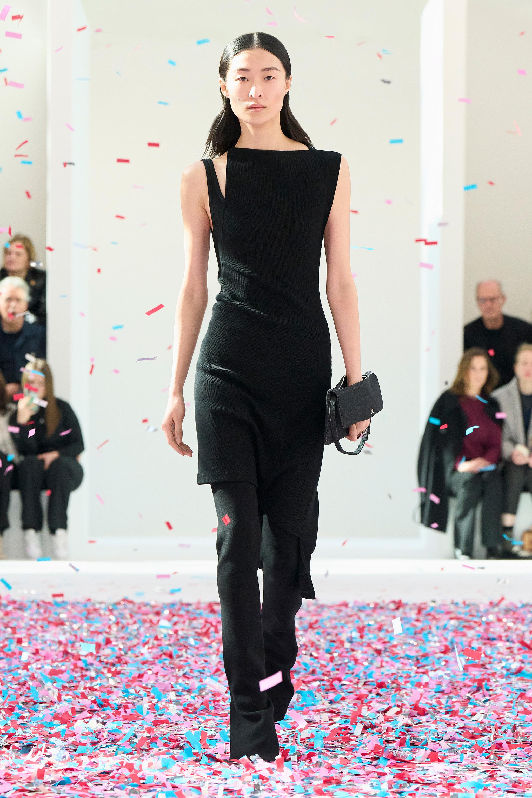 Elegant black dress by Courrèges showcased on a runway with colorful confetti for an ecommerce site.