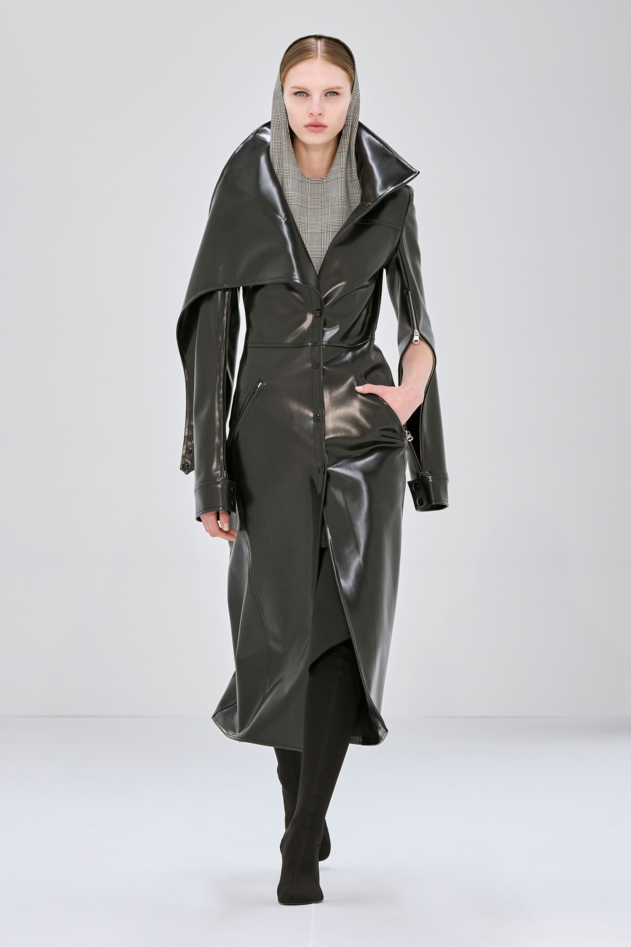 Elegant black trench coat with high collar, designed for Courrèges fashion, on a runway model.