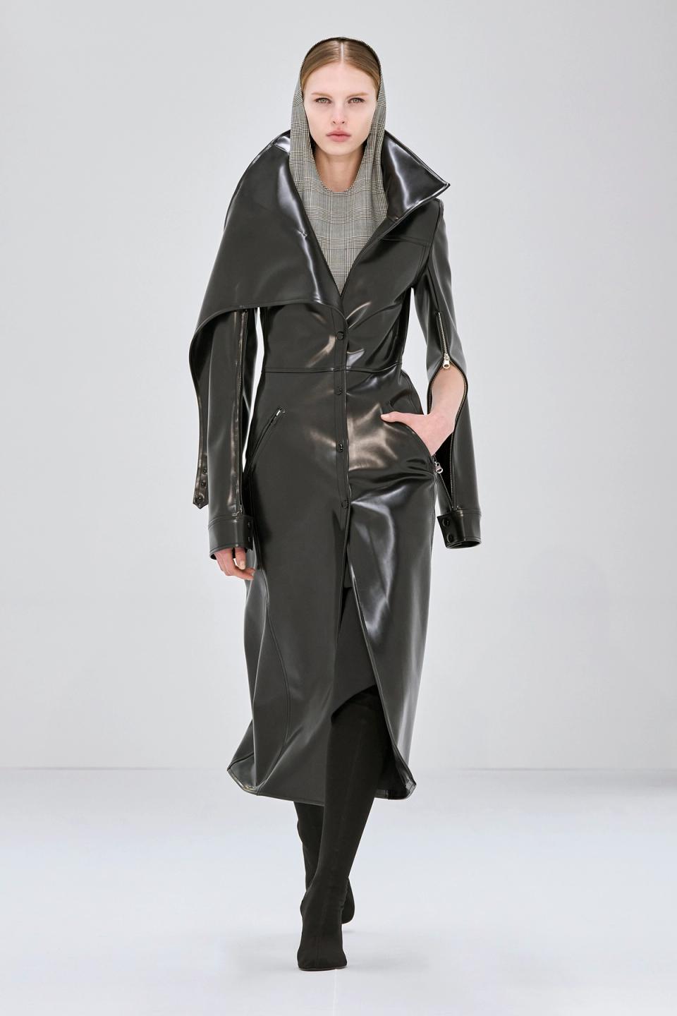 Elegant black trench coat with high collar, designed for Courrèges fashion, on a runway model.