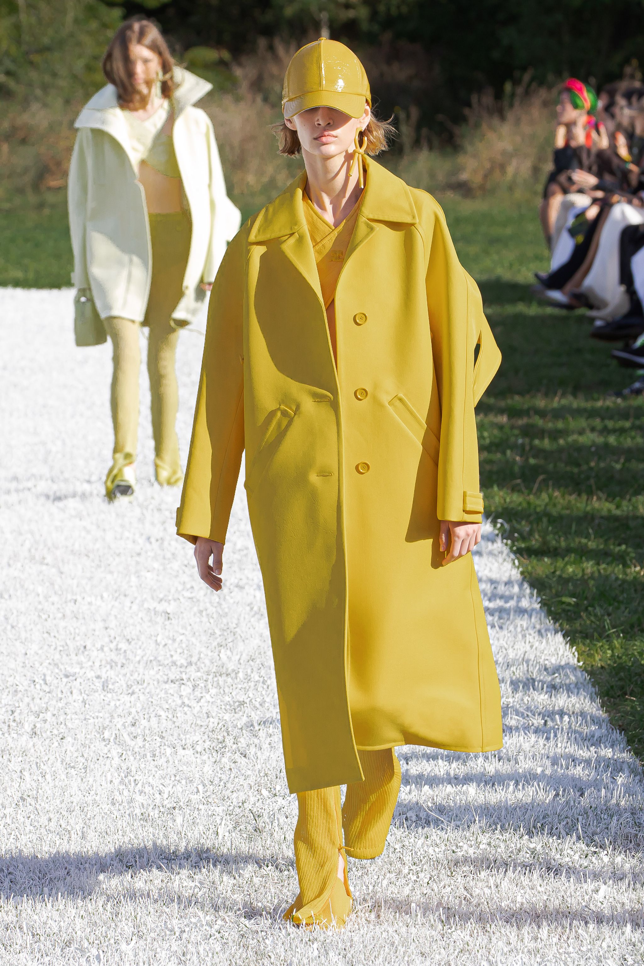 Elegant yellow trench coat and matching accessories showcased on a runway for Courrèges.