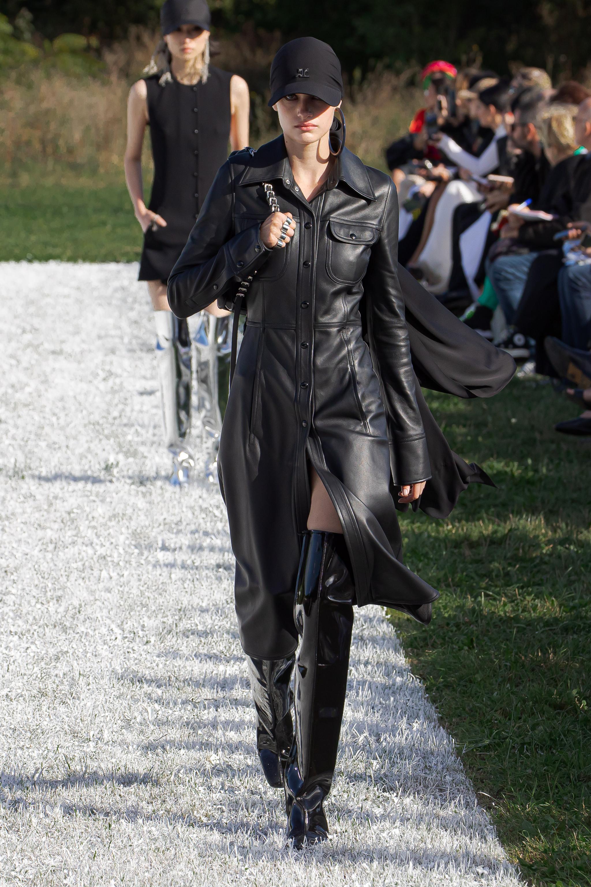Elegant black leather dress with high boots showcased on a Courrèges runway at fashion event.