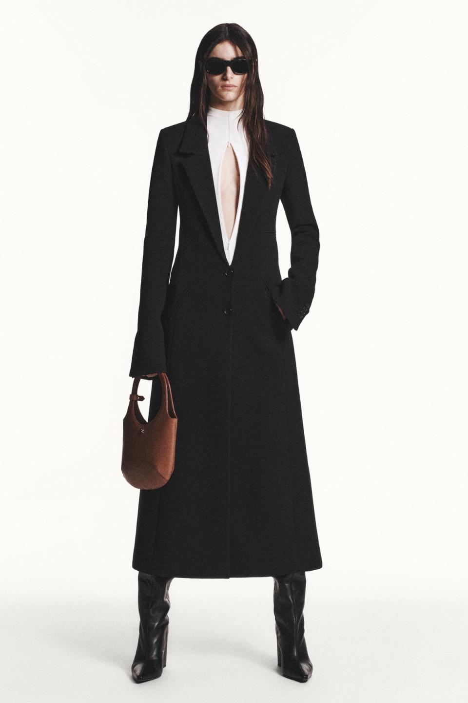 Elegant black blazer with a daring slit, paired with sheer tights, sunglasses, and high heels for Courrèges.
