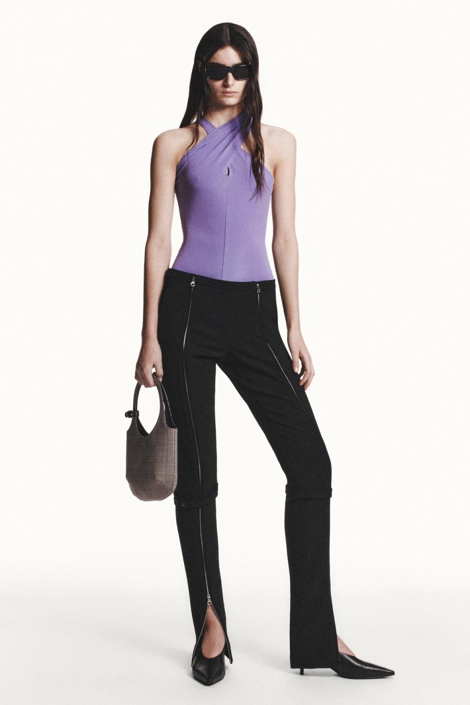 Elegant purple top and black pants with zippers, model wearing Courrèges fashion for women.