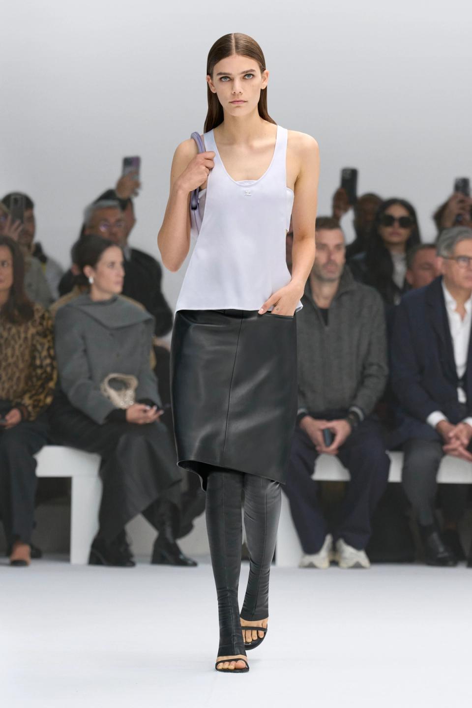 Elegant Courrèges fashion showcase featuring a model in a white top and black leather skirt.