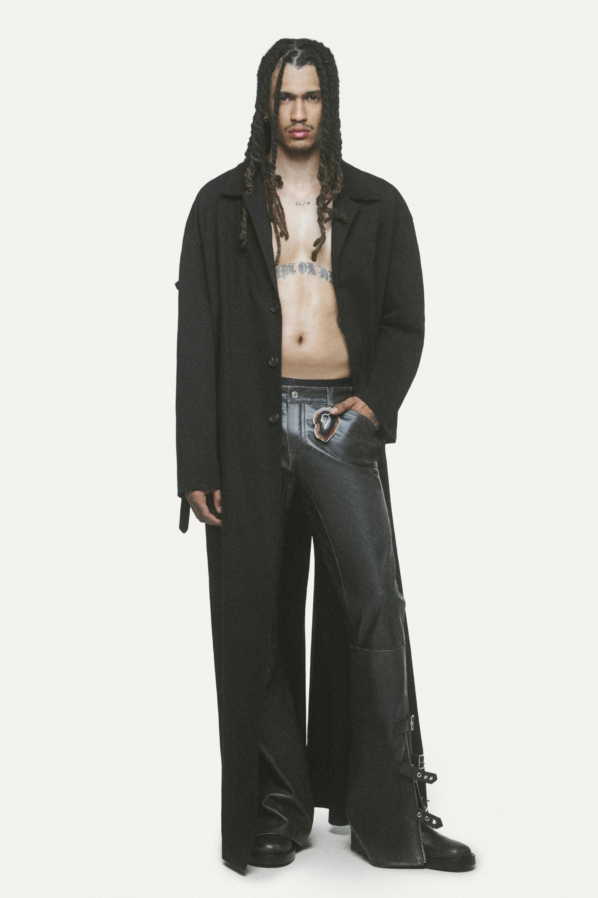 Fashion model wearing black leather pants and a black coat for Courrèges clothing collection.