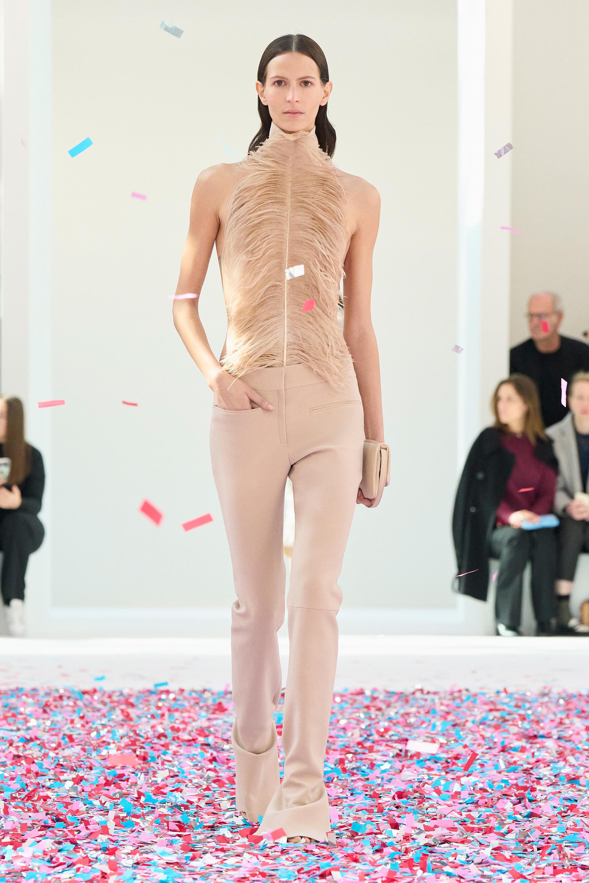 Elegant beige fashion outfit on runway, Courrèges brand, with confetti for an ecommerce display.