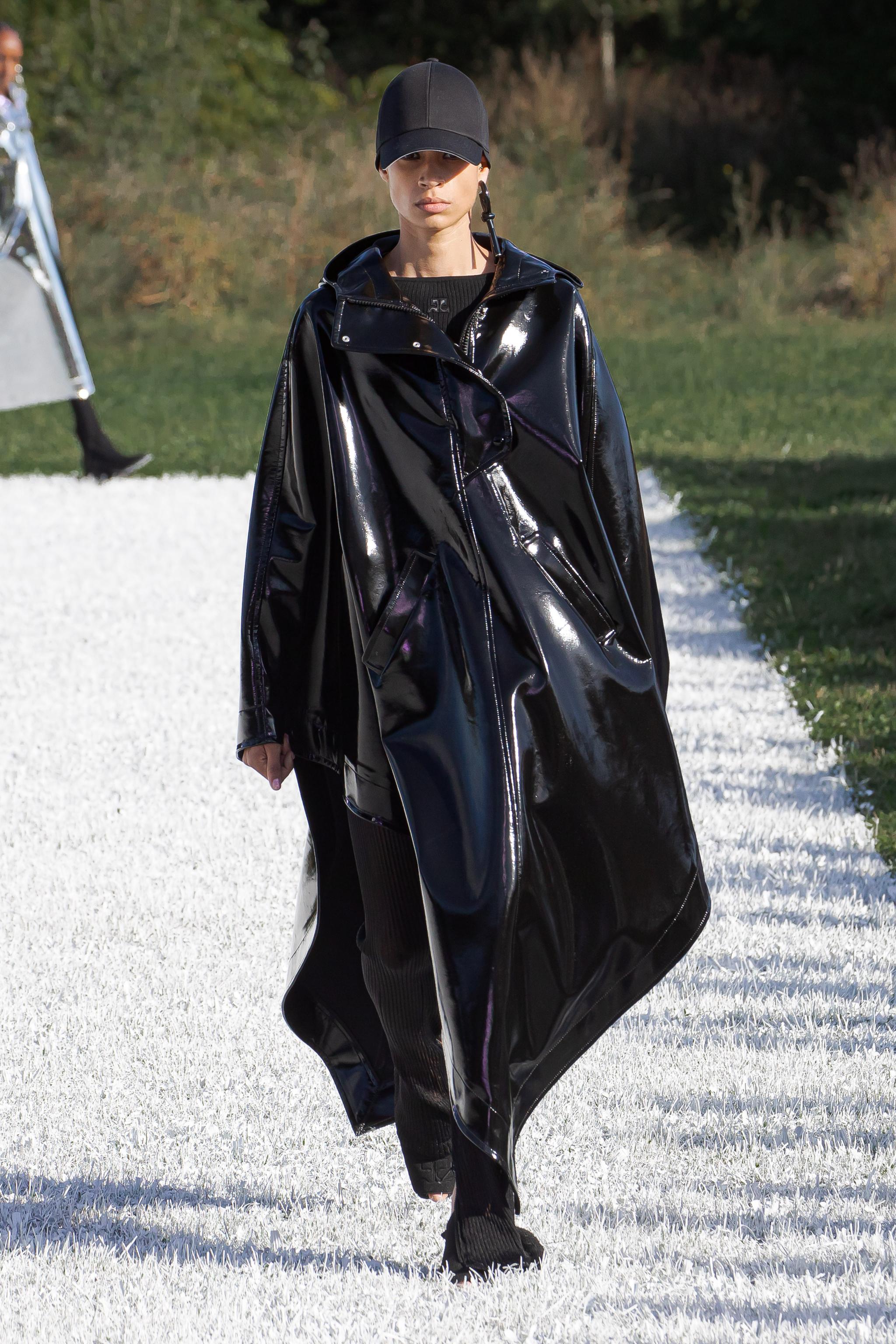 Elegant black shiny raincoat by Courrèges on a fashion runway, perfect for modern style.