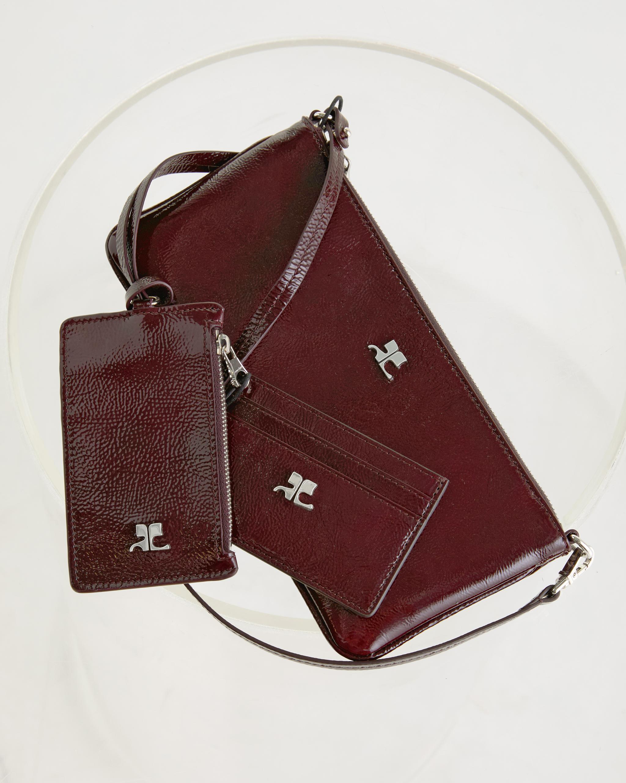 Elegant burgundy leather handbag with matching wallet, stylish accessories by Courrèges.
