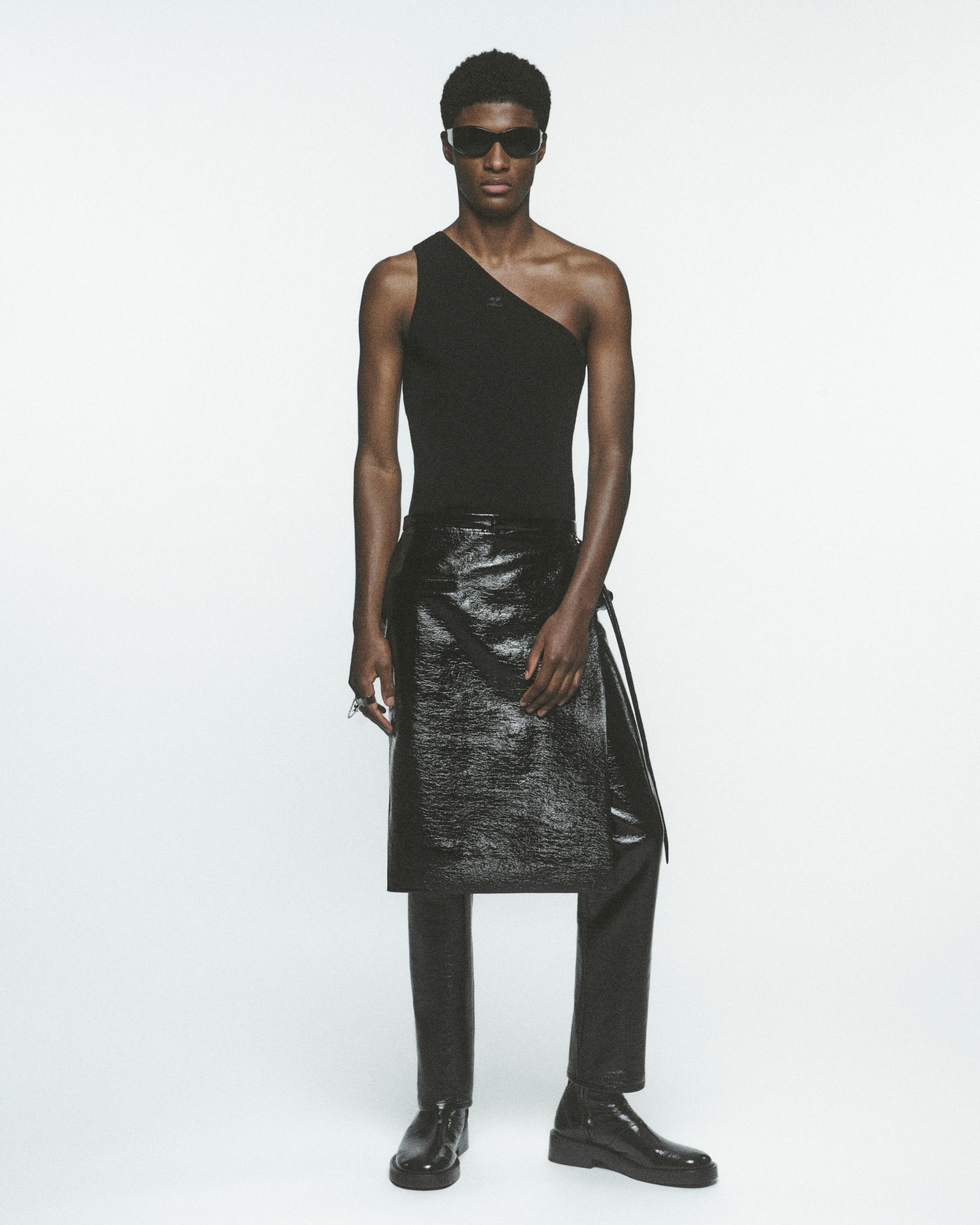 Elegant model wearing a black asymmetrical top, leather skirt, and sunglasses for Courrèges fashion.