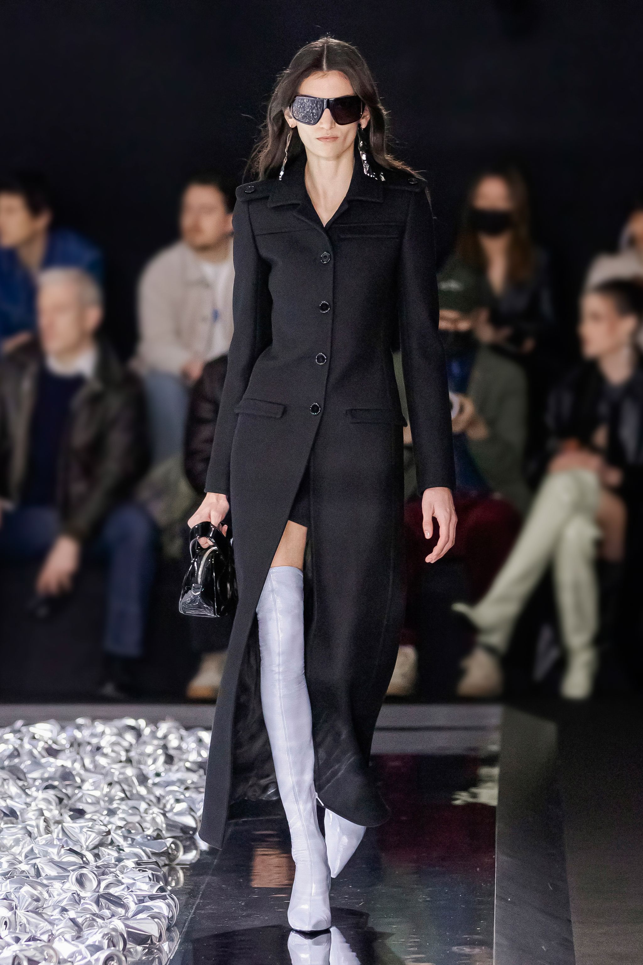 Elegant black coat with stylish thigh-high white boots on a fashion runway for Courrèges.