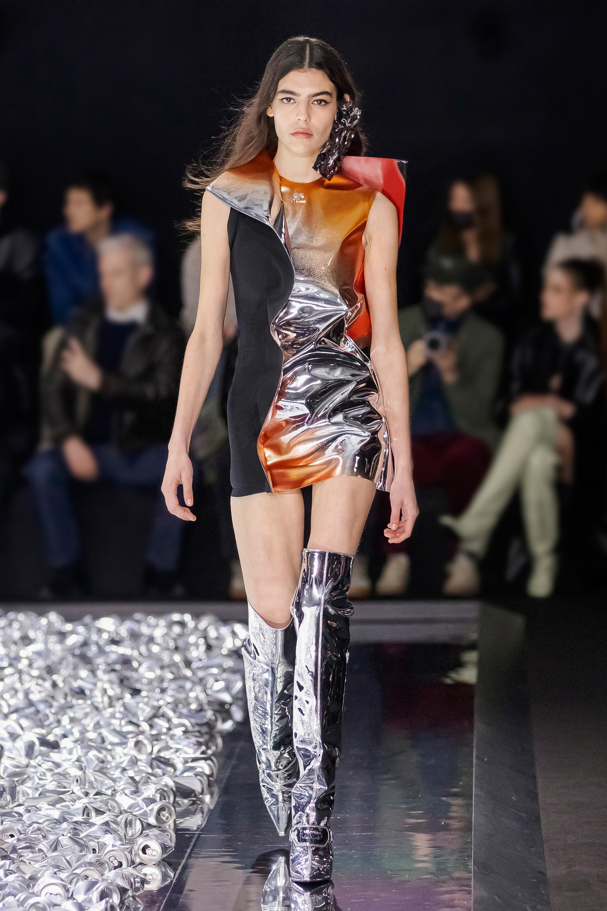 Elegant model walking on runway in metallic and fabric dress for Courrèges fashion show.