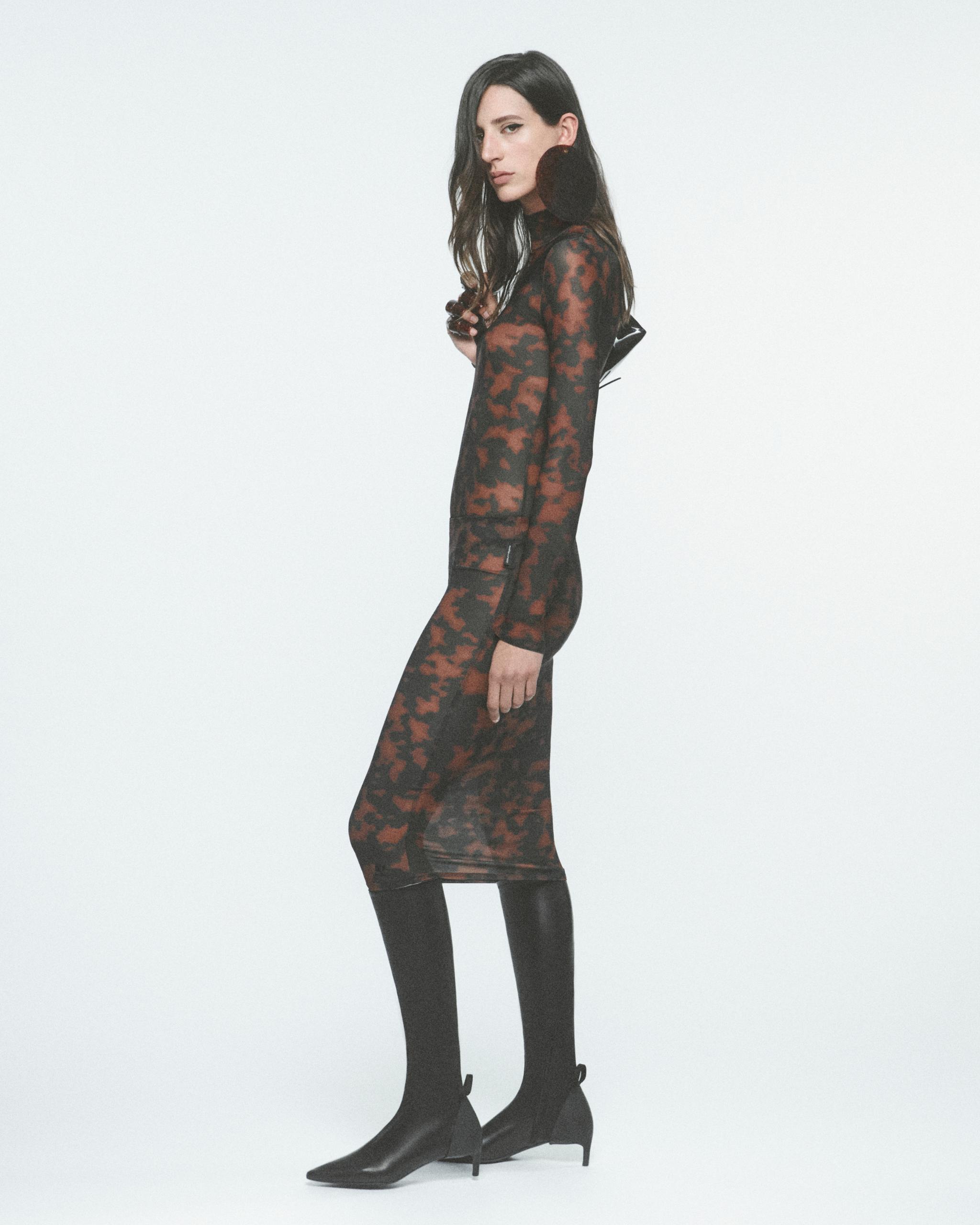Elegant model wearing Courrèges fashionable camouflage dress with high boots, Parisian style.