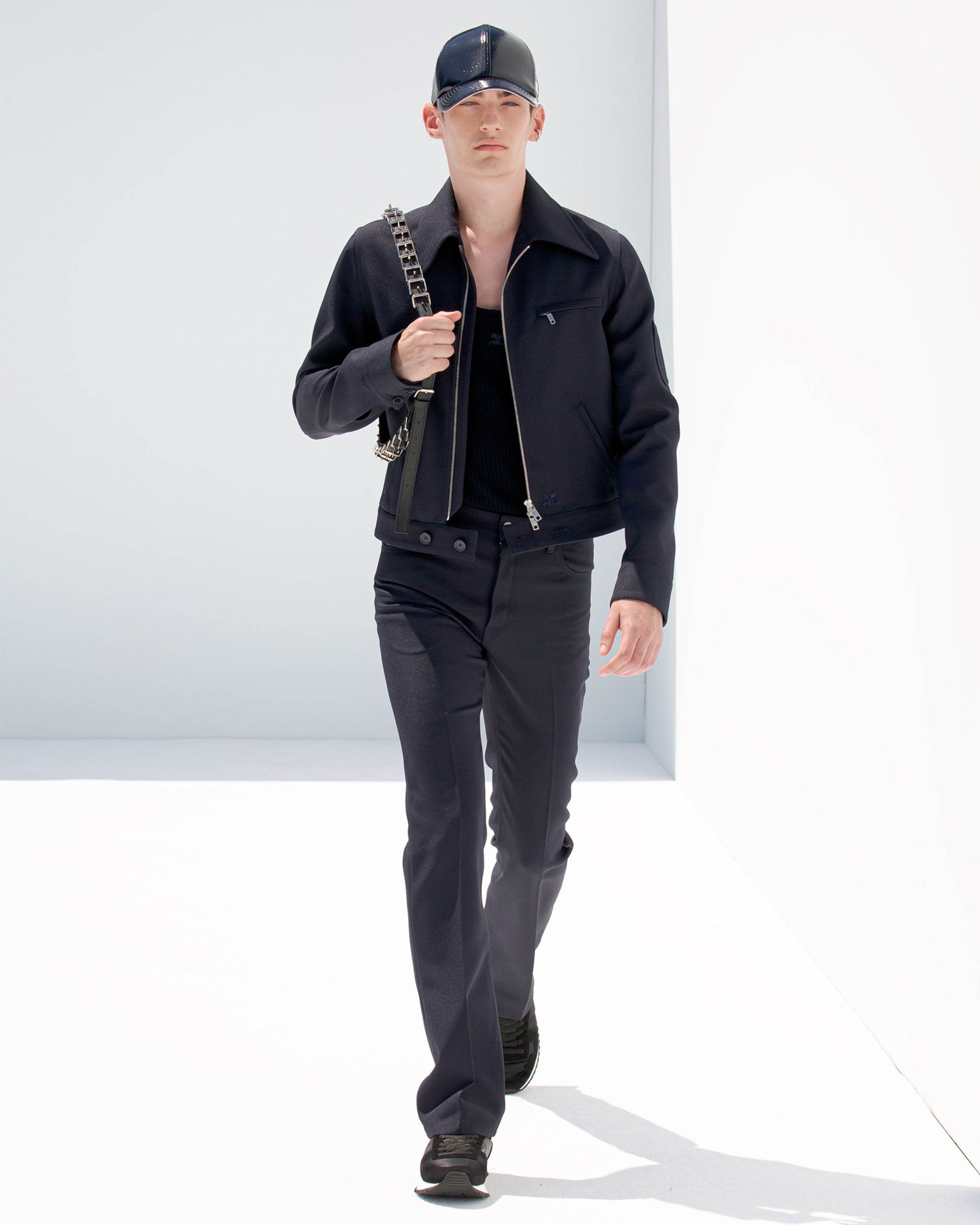 Elegant black jacket, pants, and accessories from Courrèges in a sleek, modern fashion display.